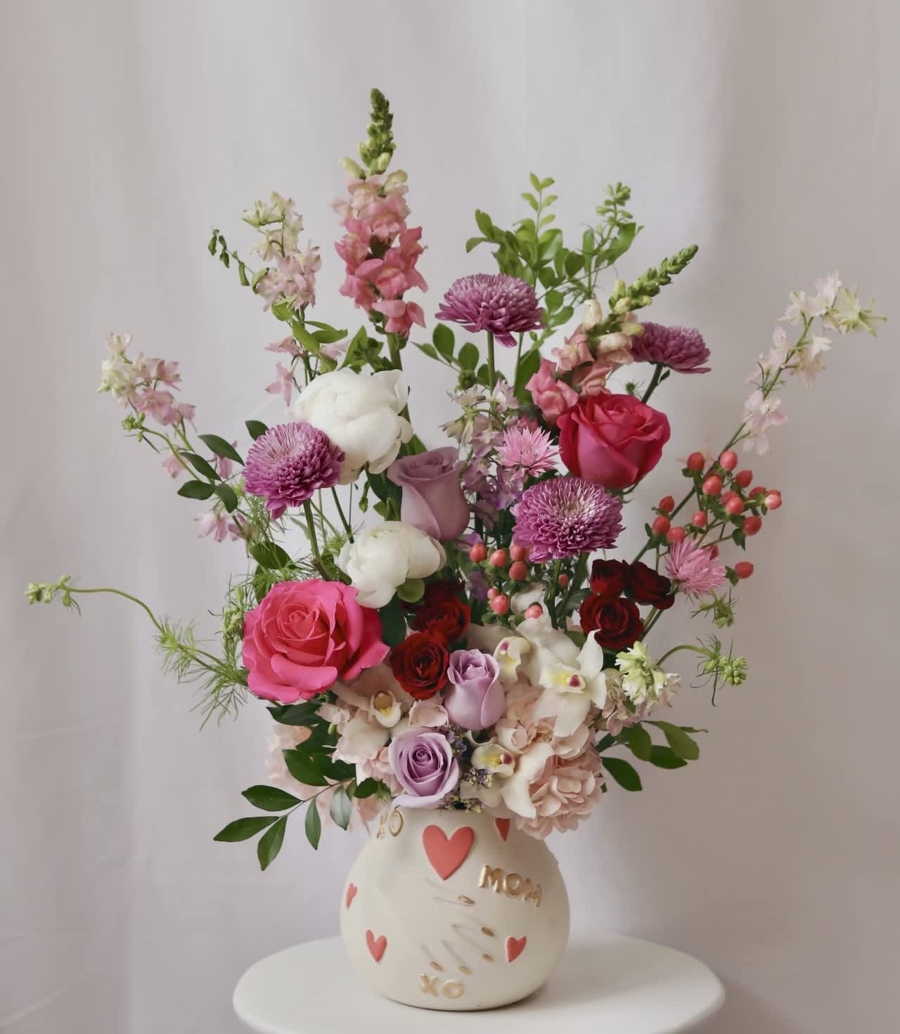 Mixed pink and white flower arrangement in a cream vase with heart decorations