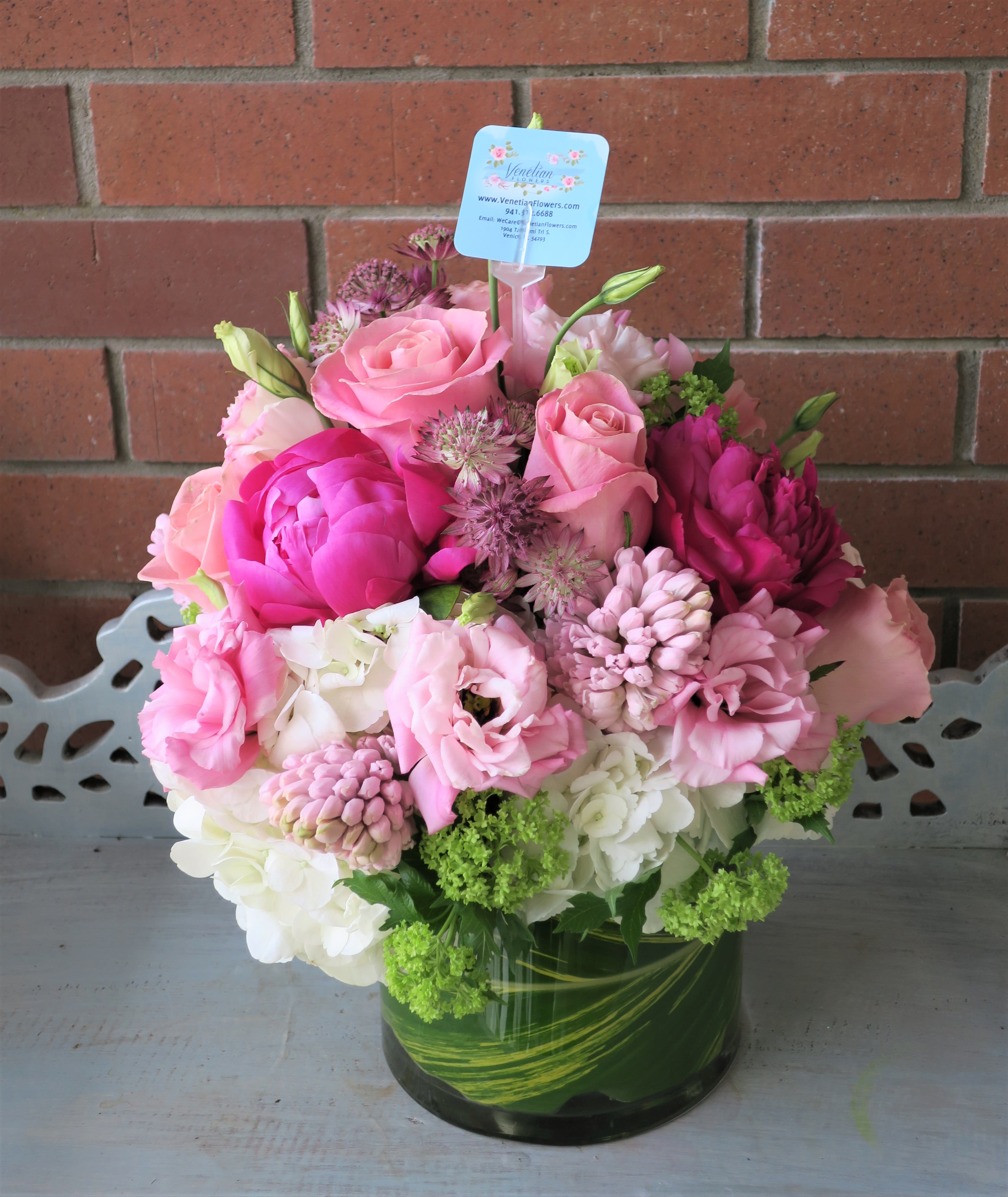 Pink and white flower arrangement with roses, peonies and hydrangeas in a glass vase with leaf wrap