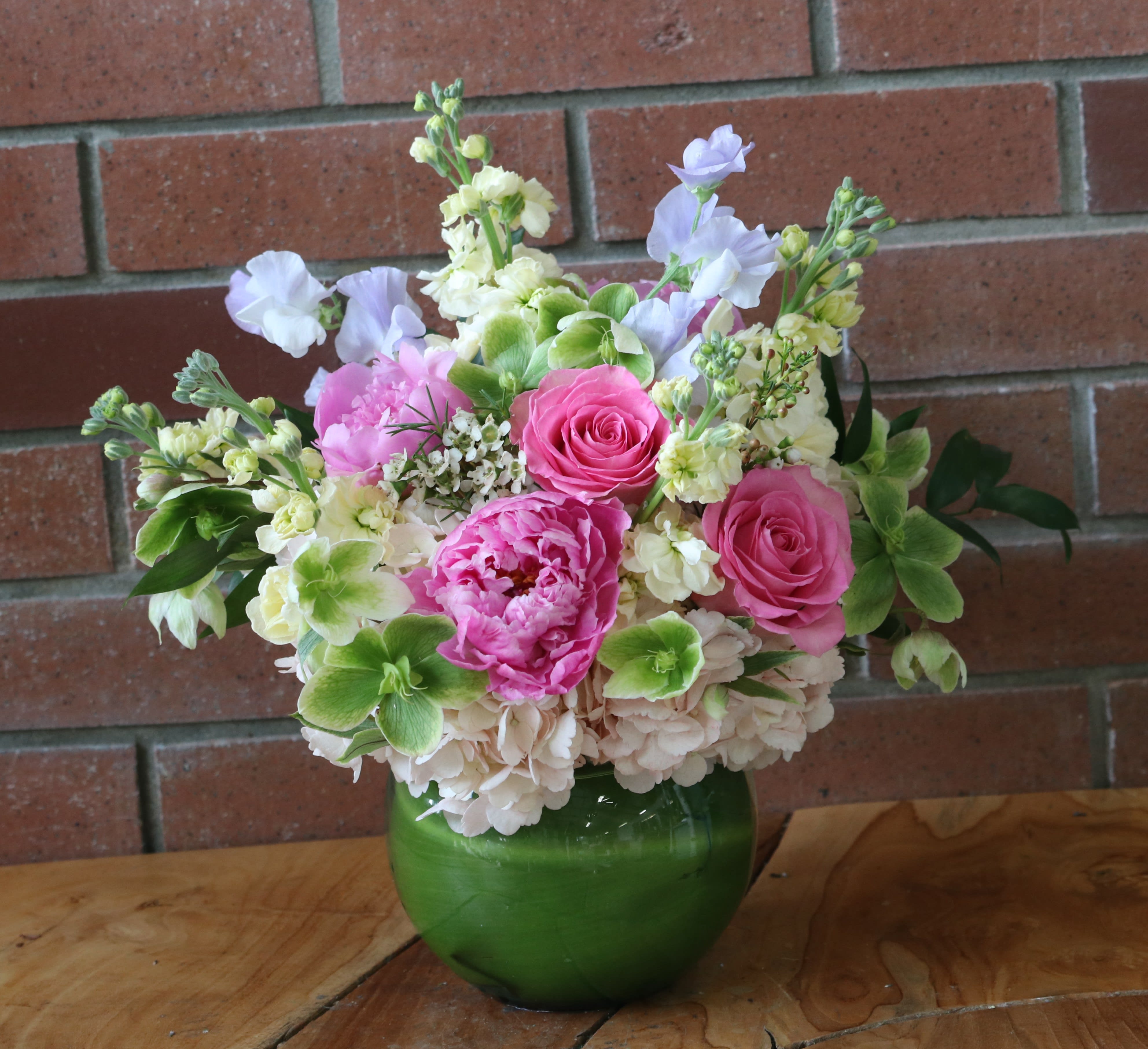 Pink and white flower arrangement in a green glass vase