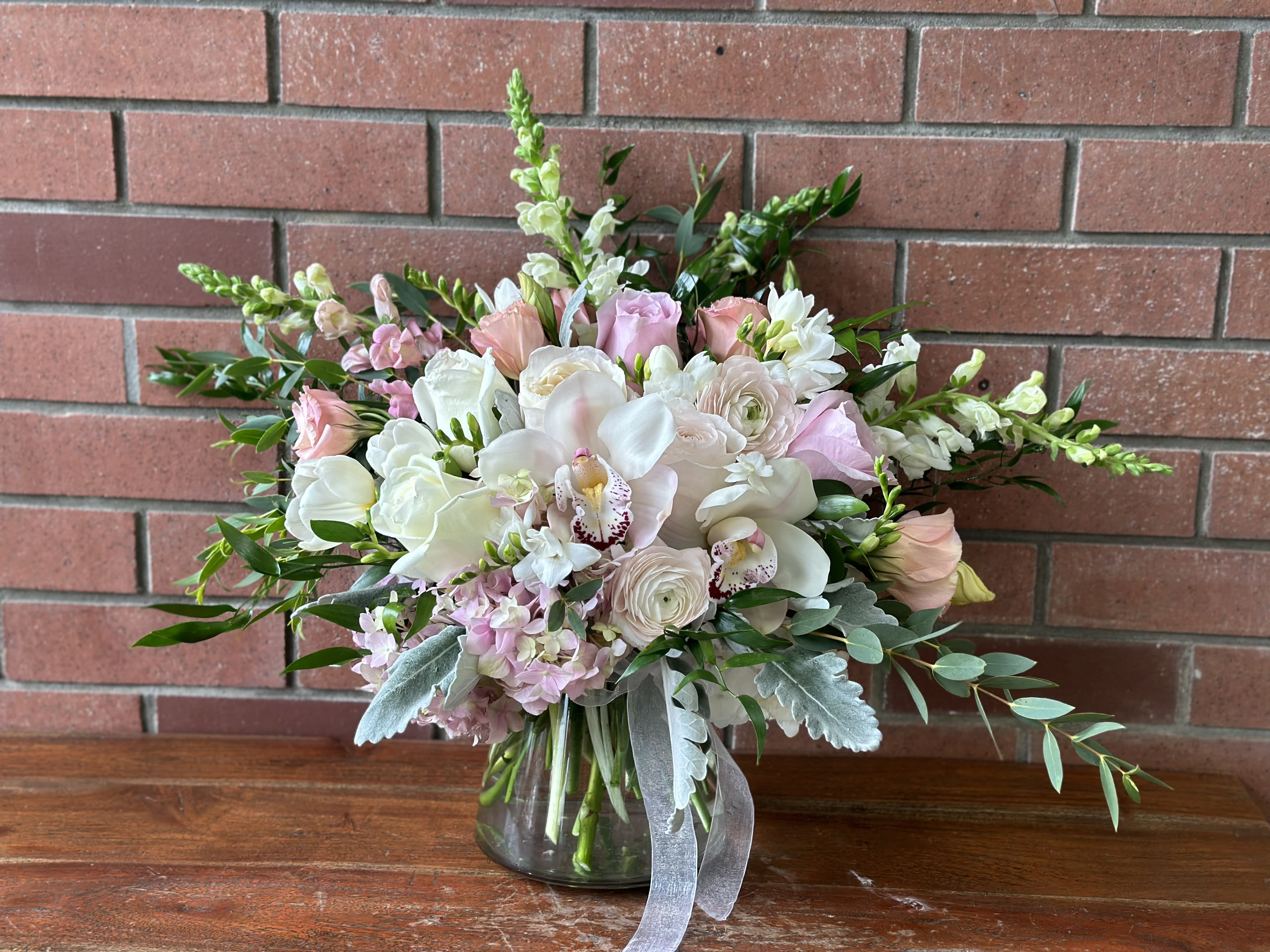 Pink and white bouquet in a glass vase with trailing greenery
