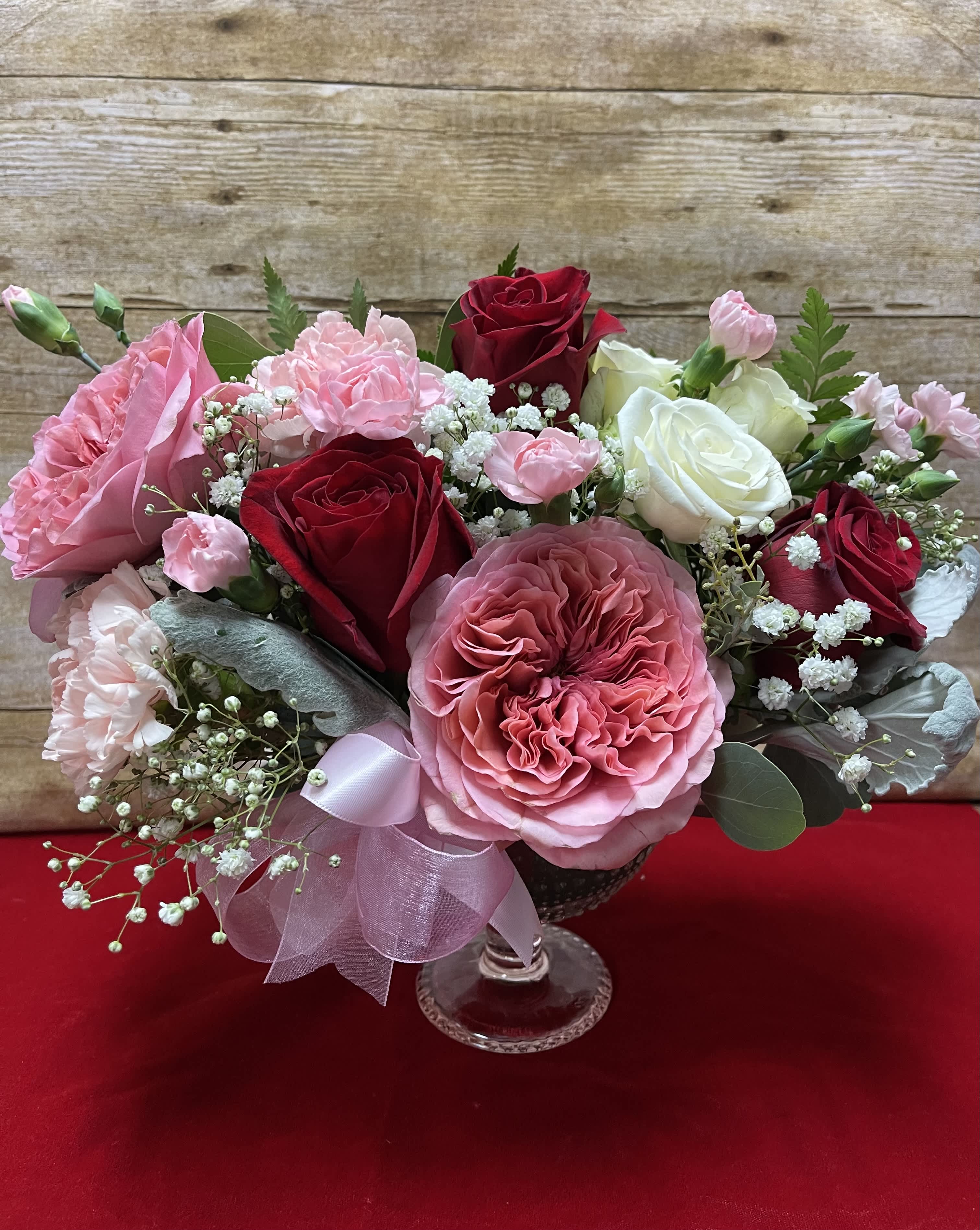 Pink and red rose bouquet in a clear glass vase with baby's breath