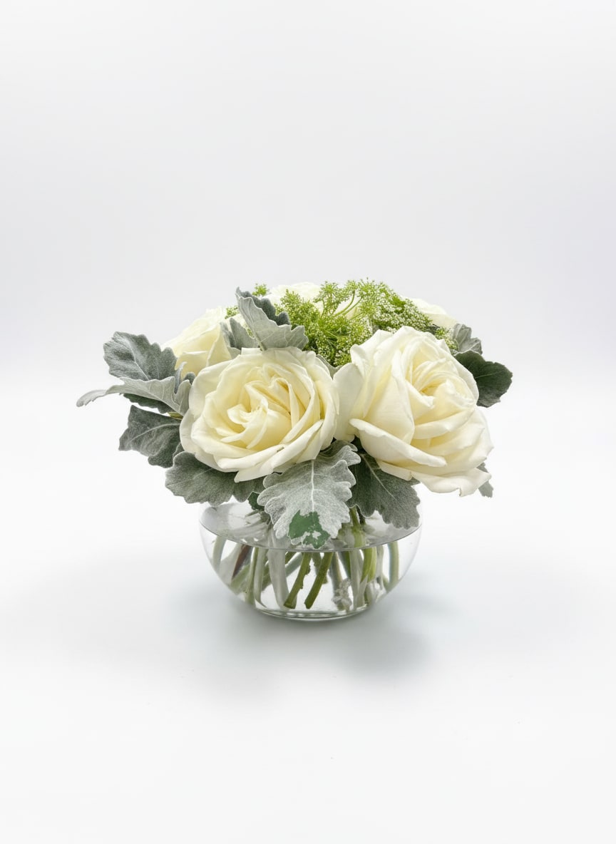 Simple Elegance - Creamy Playa Blanca roses with dusty miller and Queen Anne's lace in a low clear glass bowl - tabletop-ready. Simple, classic and elegant. Add a little something extra, gourmet chocolates, hand poured candles. See all our gift selections under the thoughtful gifts tab. Or call the shop and let us know what you are looking for and we will do the shopping for you.