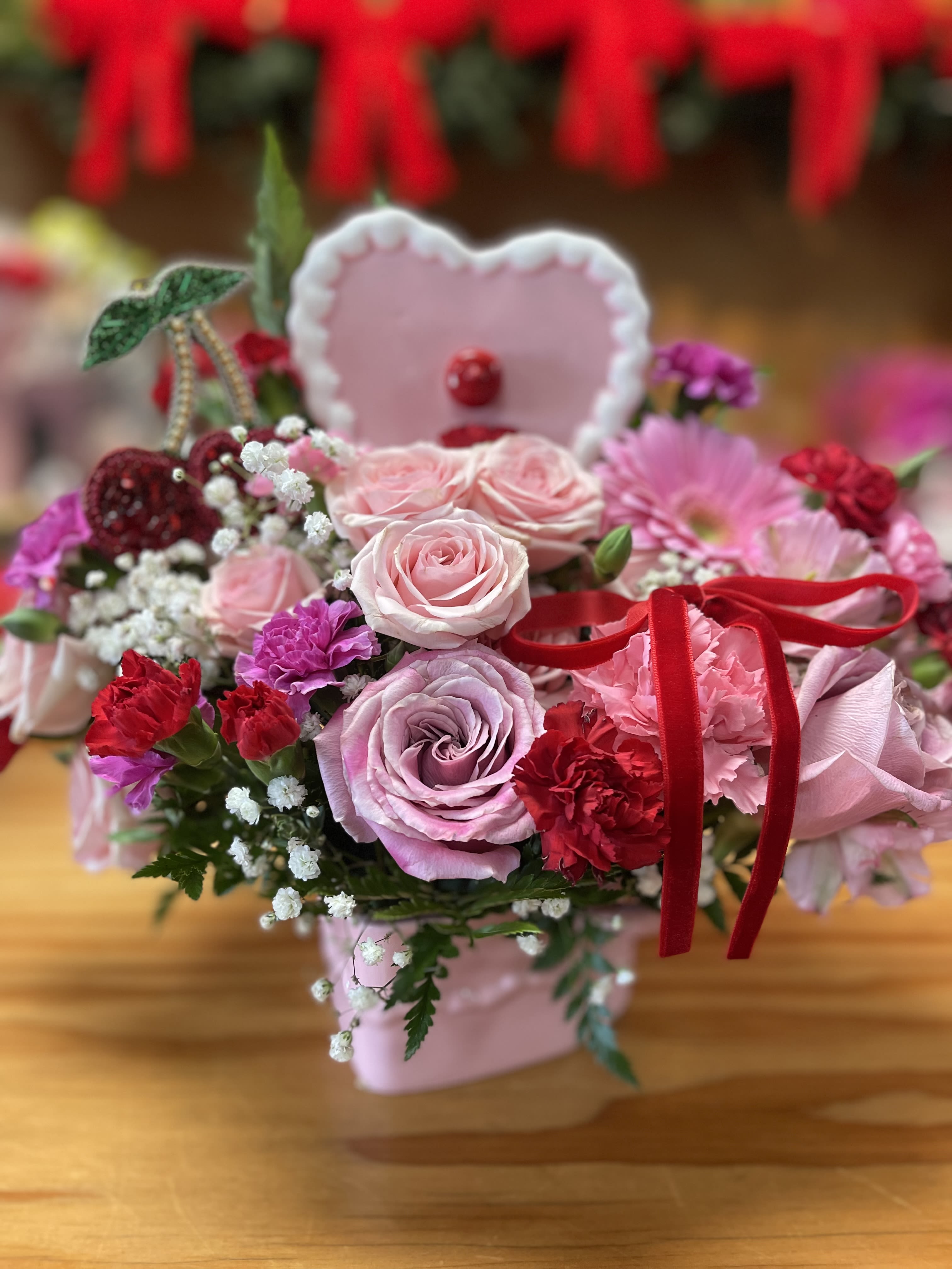 Pink rose bouquet with red carnations and a heart topper in a pink box