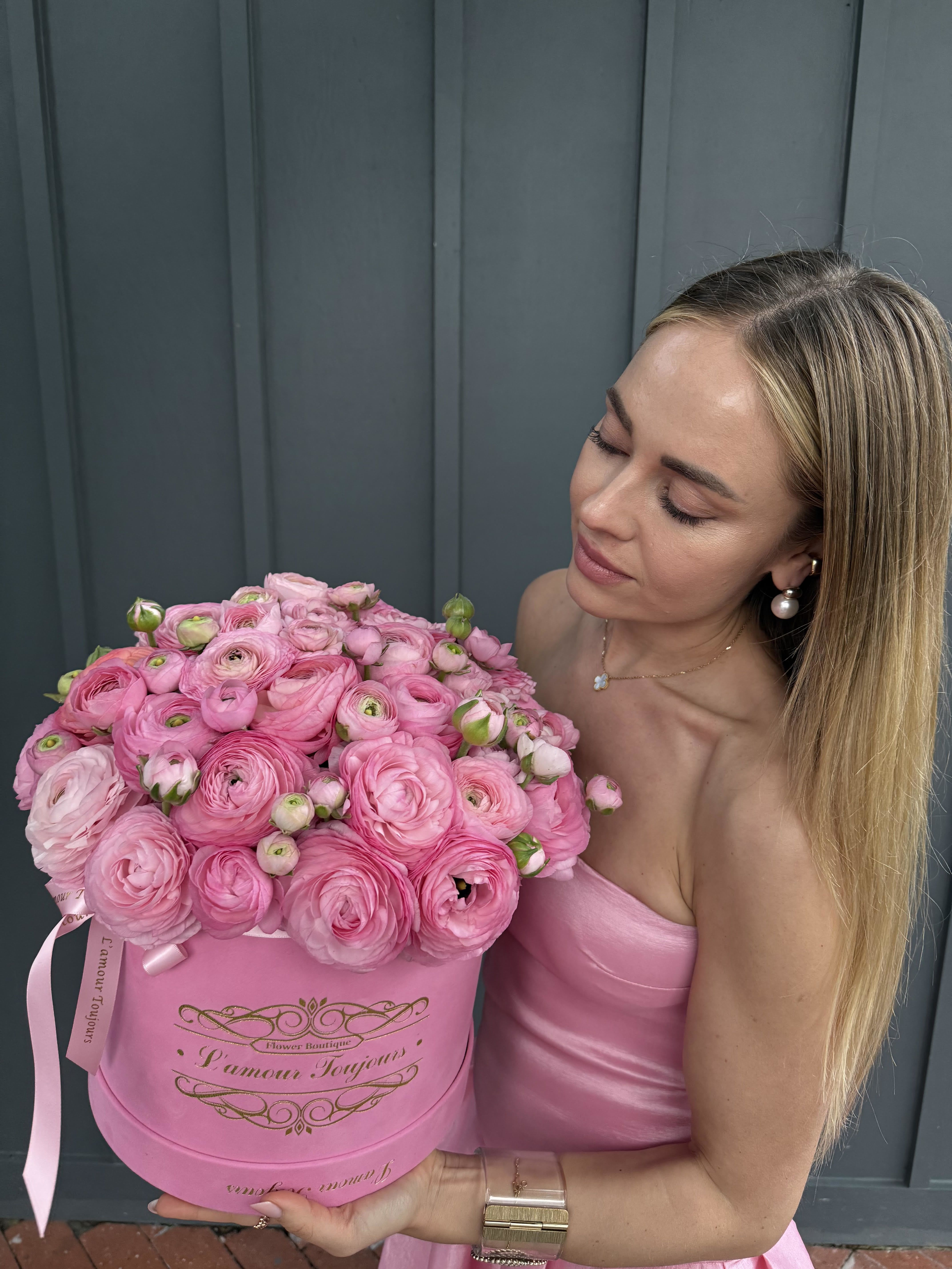 Woman holding a large pink box of pink ranunculus flowers
