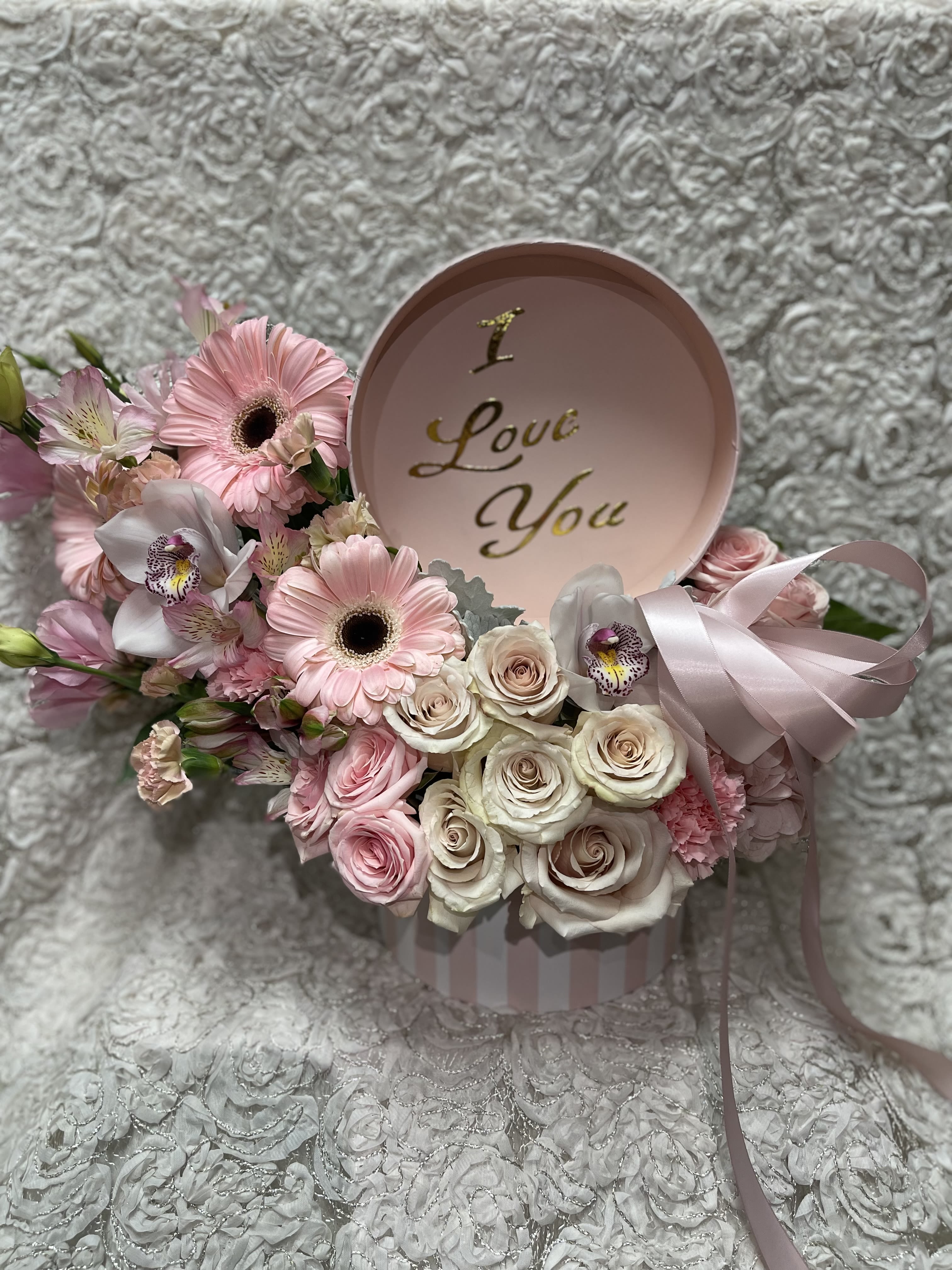 Pink and white flower arrangement in a round box with a "I Love You" lid