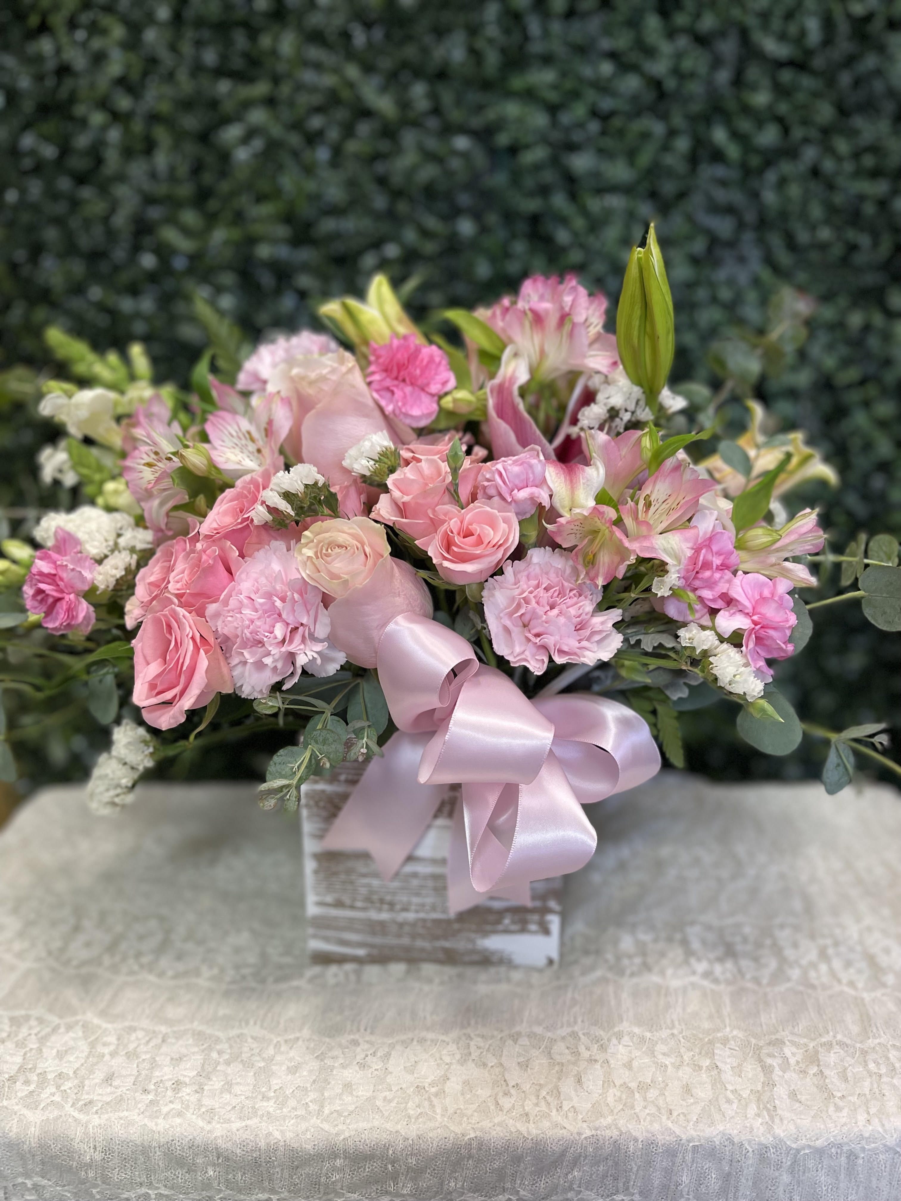 Pink bouquet of roses, carnations, and lilies in a box with a ribbon