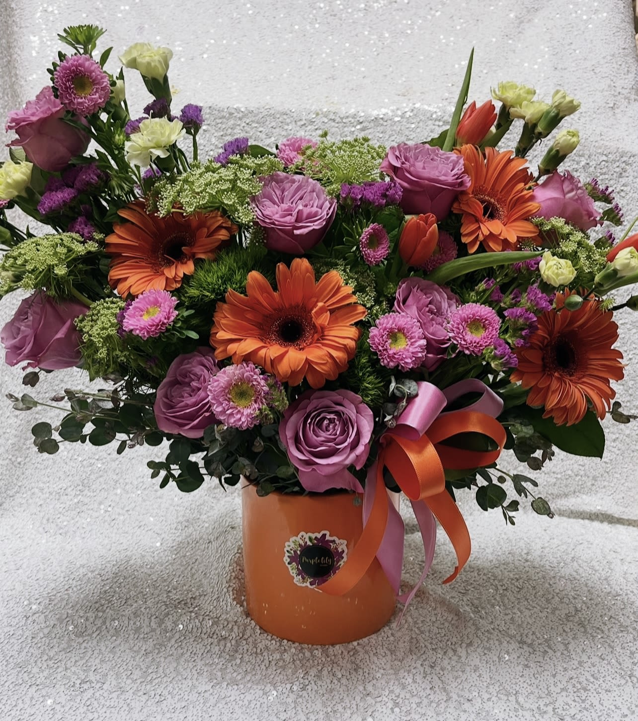 Bouquet of pink roses and orange gerbera daisies in an orange vase