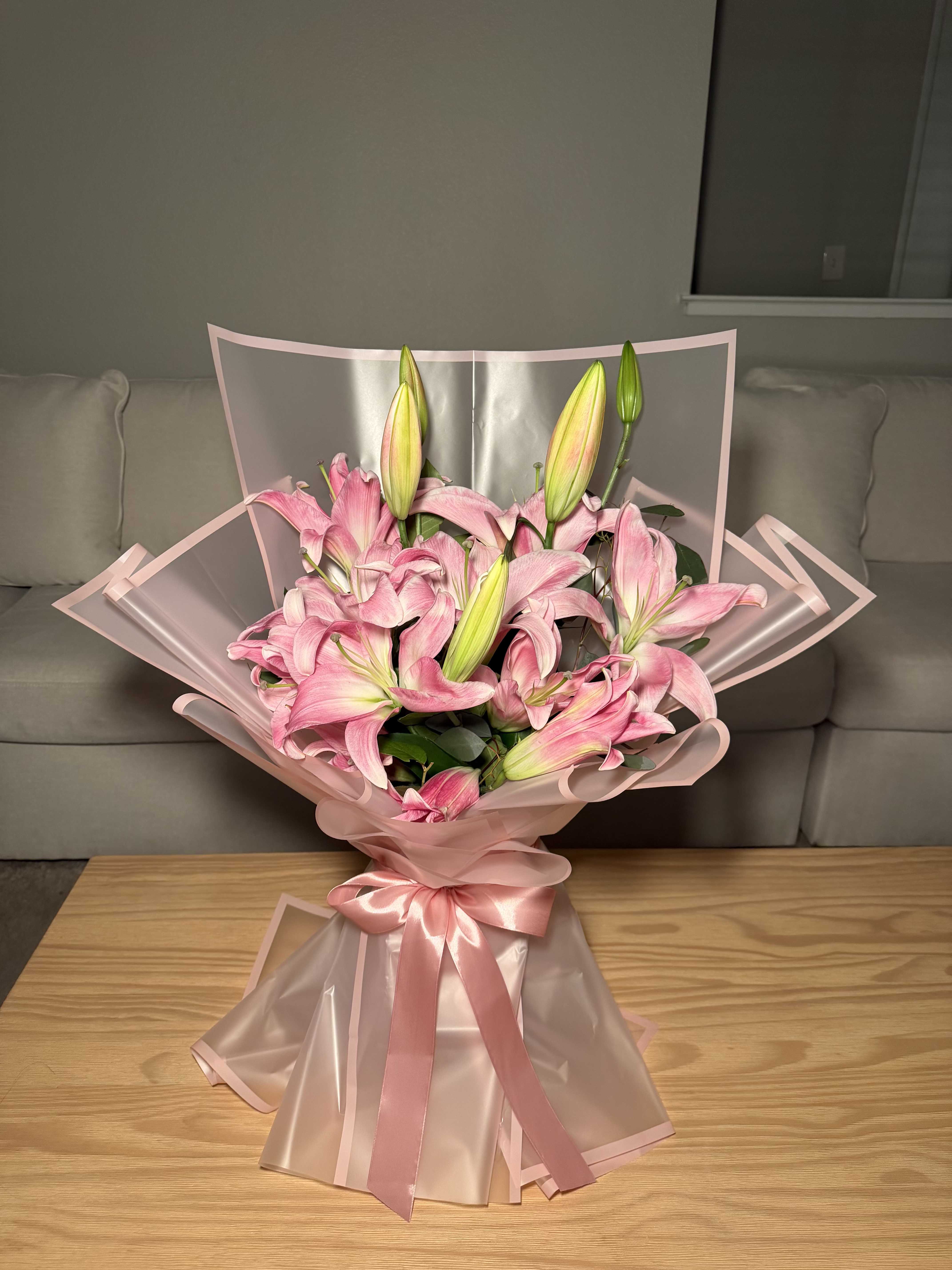 Lily Blush Luxury - Our Lily Blush Luxury bouquet  is a breathtaking floral design created to impress at first sight. Made with premium pink lilies, fresh greenery, and wrapped in luxurious Korean-style paper finished with a satin ribbon, this bouquet represents elegance, softness, and sophistication.  Each lily blooms beautifully over time, revealing its natural beauty and fragrance, making this arrangement the perfect gift for birthdays, anniversaries, Mother’s Day, or any special celebration.    Important: This bouquet includes a special hydration base to help keep the flowers fresh longer.  We recommend NOT taking the bouquet apart or removing the wrapping in order to preserve its original elegant design and freshness.   A luxurious, romantic, and eye-catching bouquet that makes a lasting impression.
