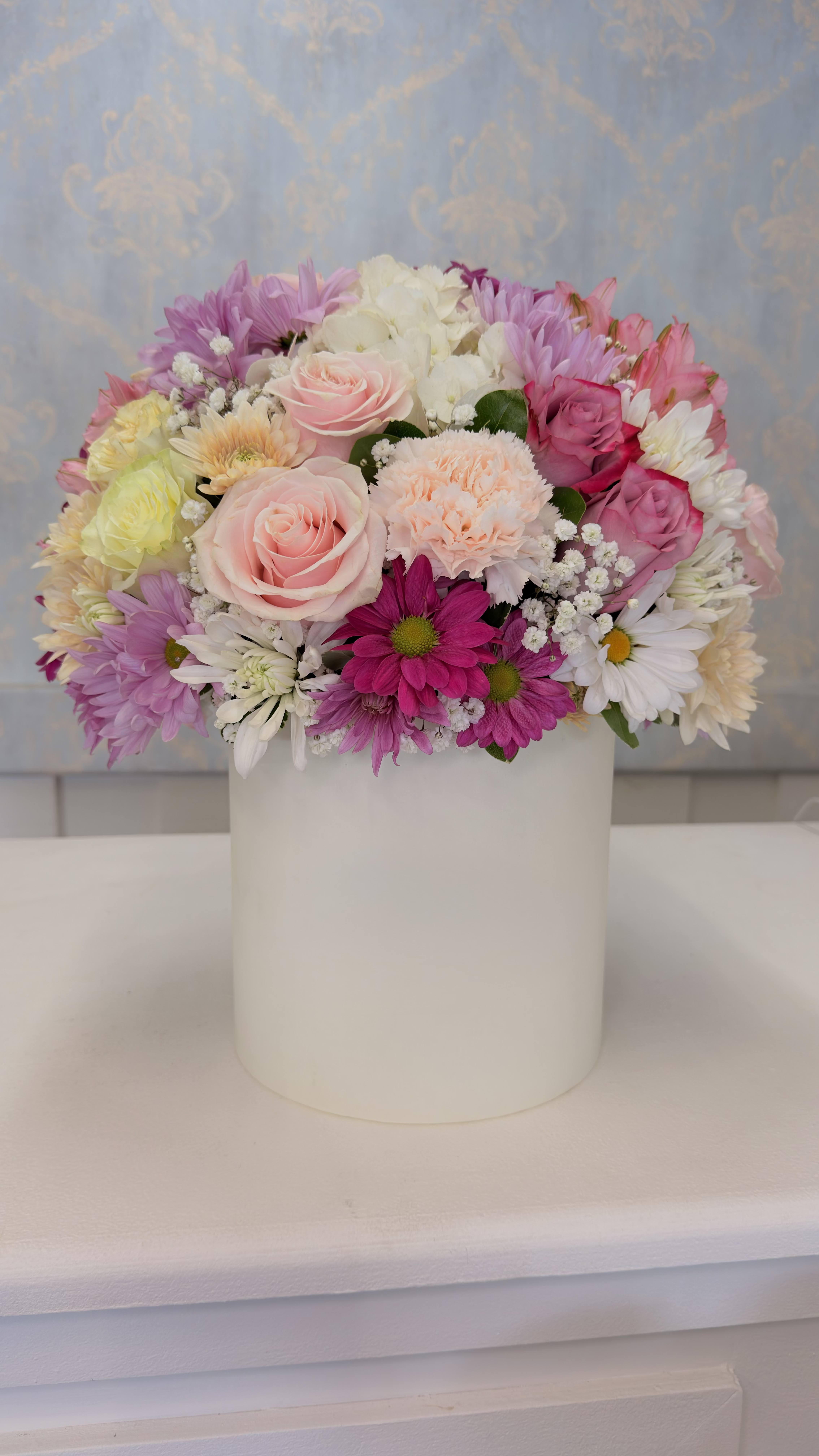 Sweet Charm – Seasonal Floral Box - A vibrant and joyful arrangement full of color and freshness, perfect for any occasion   Features a beautiful mix of roses, carnations, daisies, alstroemeria, fresh greenery, and seasonal blooms in soft and bright tones.  Designed in an elegant base, ready to enjoy with no vase needed.   A charming gift that expresses love, happiness, and elegance.