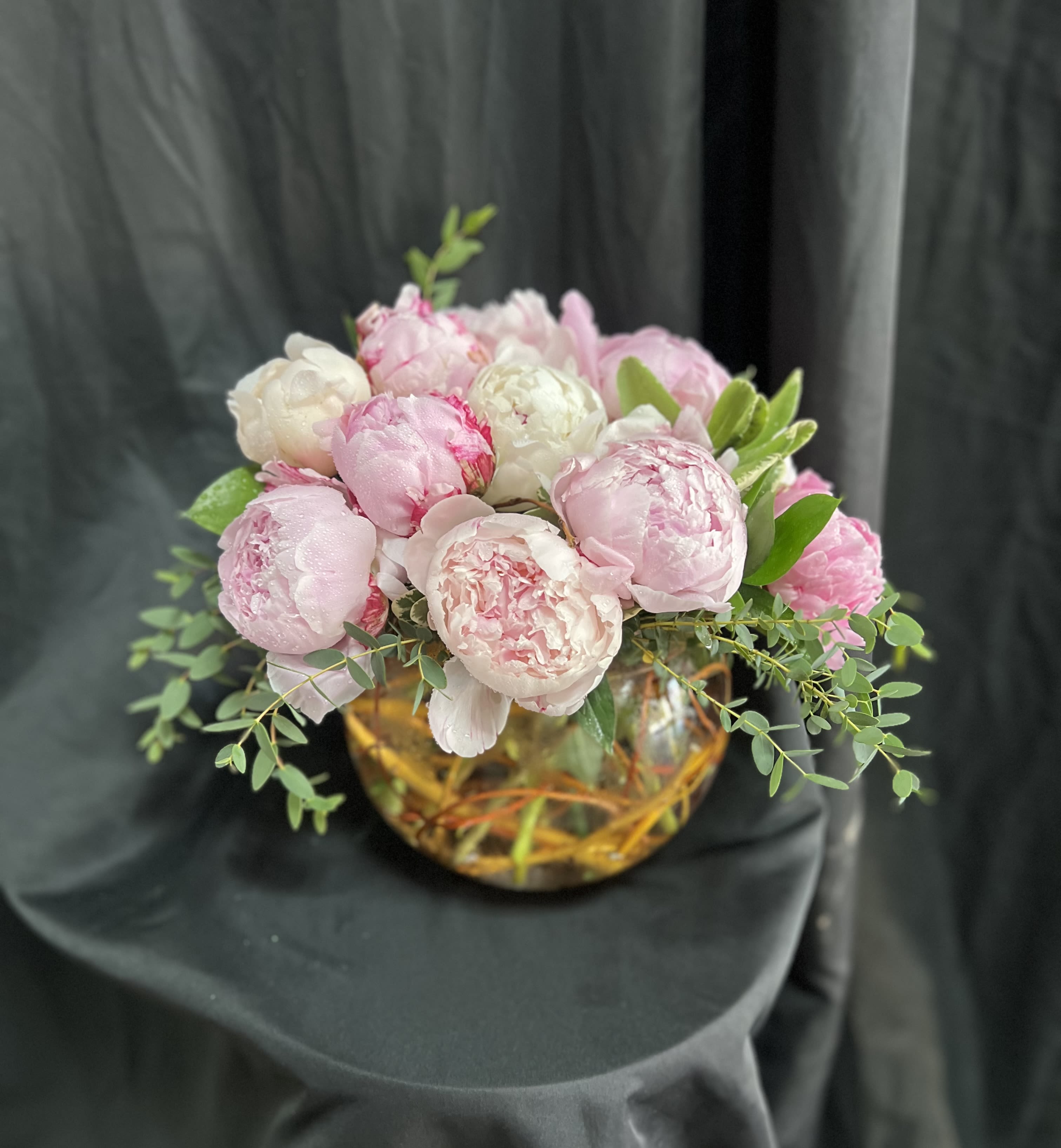 Pink and white peonies arranged in a low glass bowl