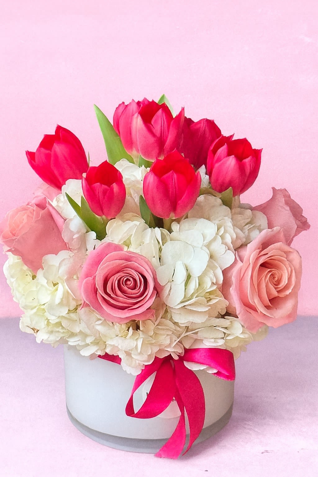 Pink Sunrise Bouquet - for the Best Mom - A charming mix of elegance and freshness, this pink and white flower arrangement captures timeless beauty. Bright tulips and soft roses bloom over a cloud of hydrangeas, accented by a bold pink ribbon. Perfect for birthdays, anniversaries, or romantic surprises, this design reflects the essence of luxury flower delivery in Los Angeles. Handcrafted by Hollywood Blooms, it brings sophistication and warmth to any moment.