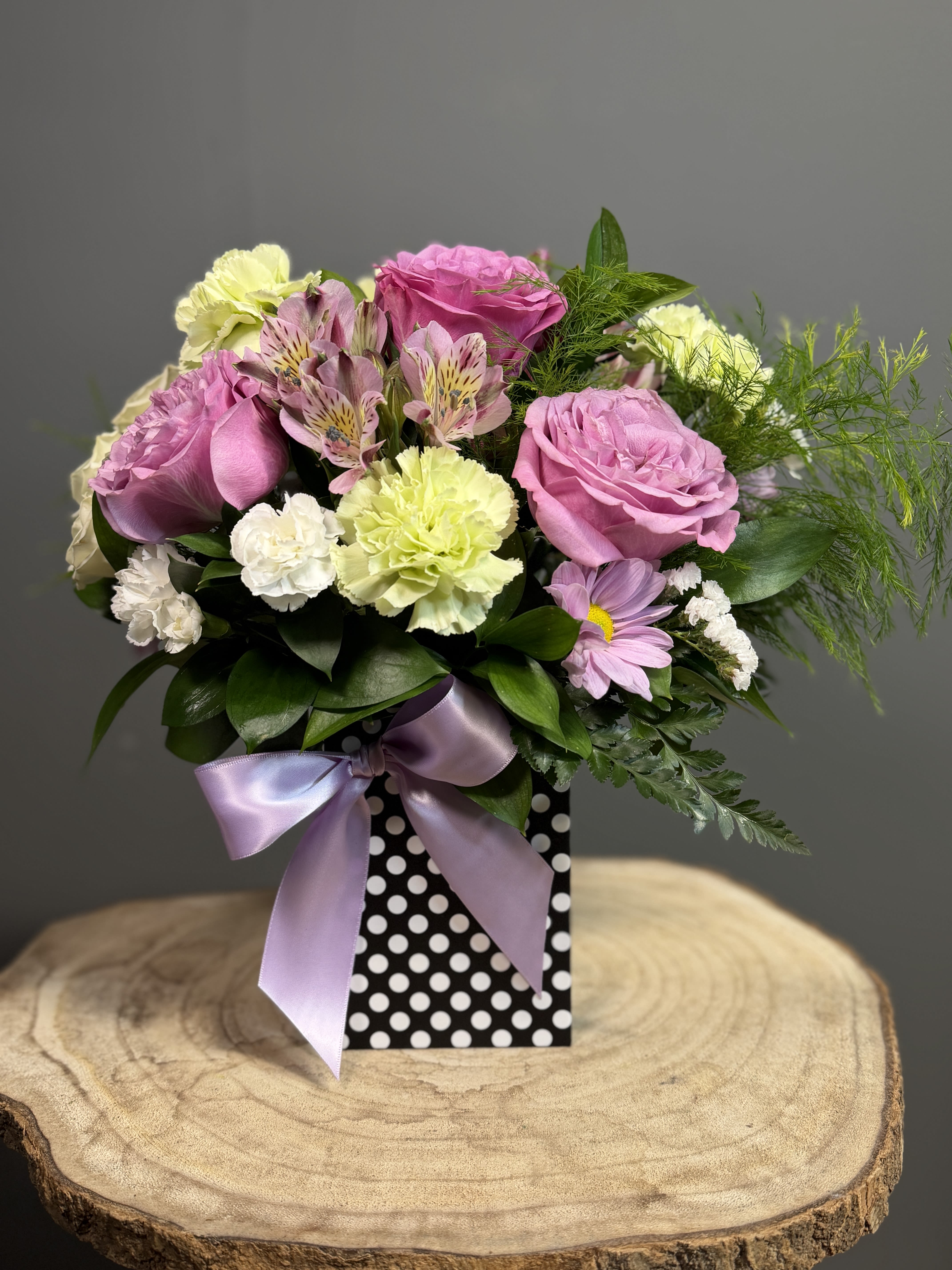 Petal Kiss  - A graceful blend of roses, alstroemeria, and carnations in gentle hues, accented with lush greenery and finished with a silky bow.