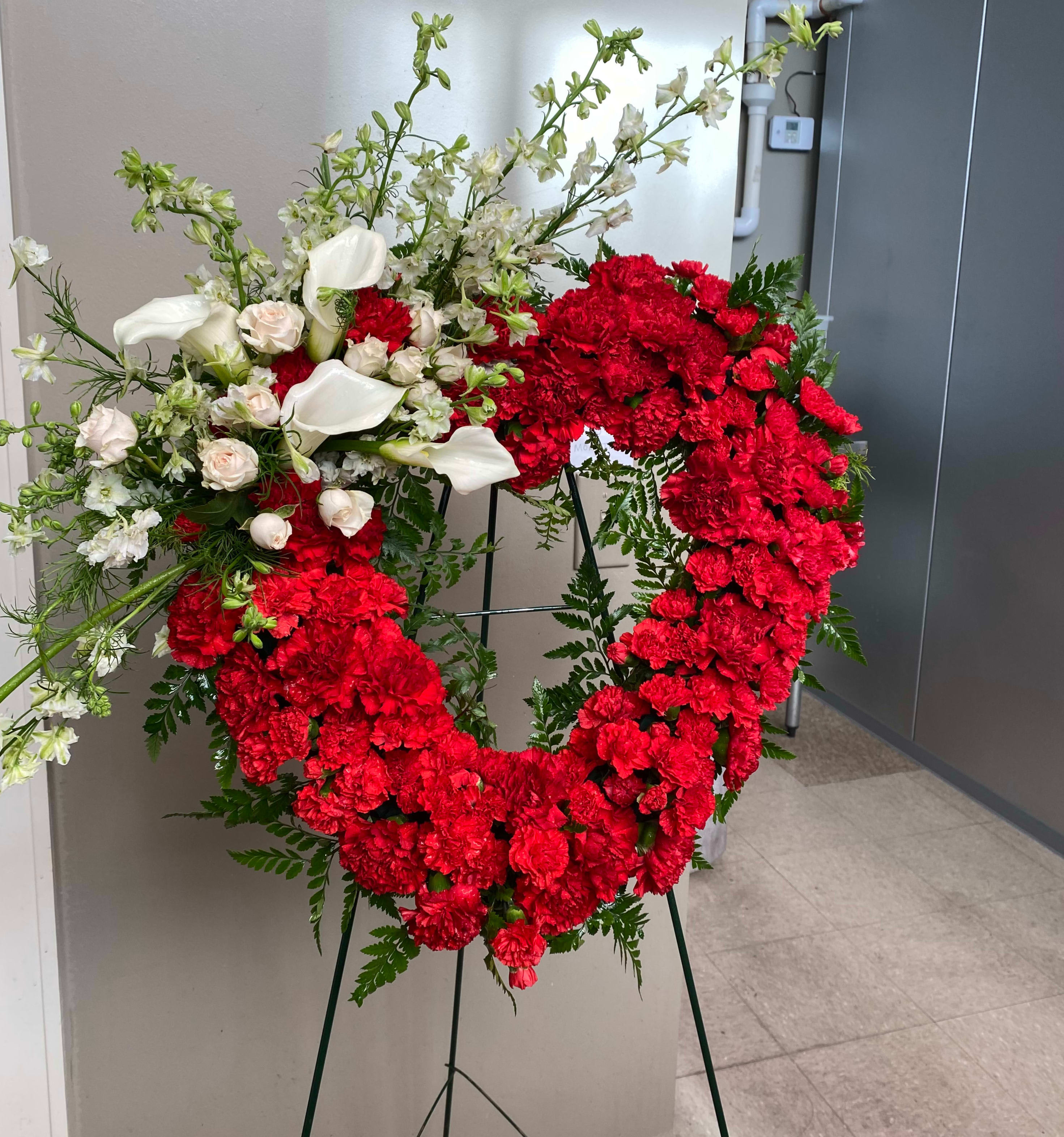 Large red and white floral wreath on a stand