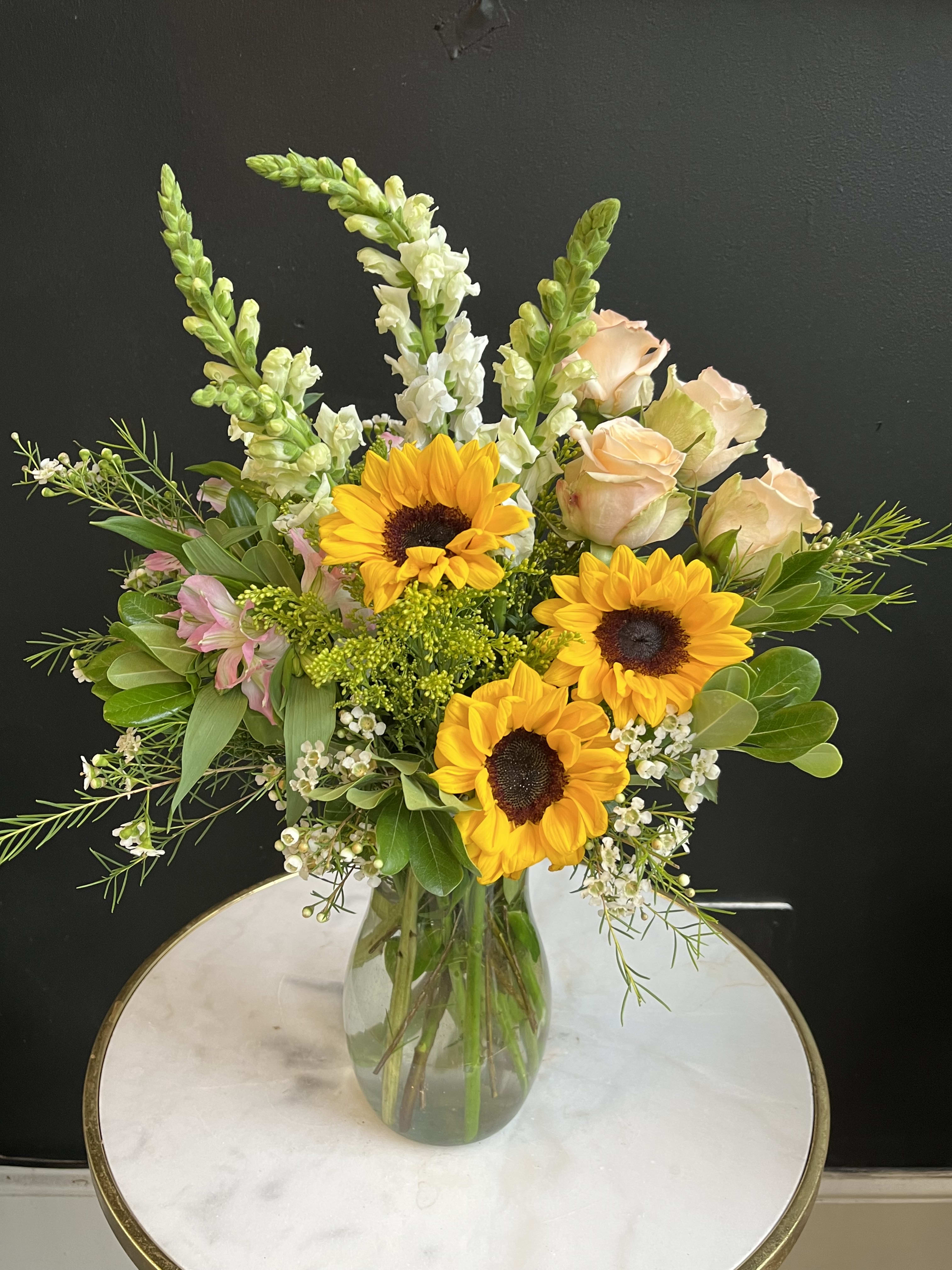 Sunflowers and pale roses in a glass vase