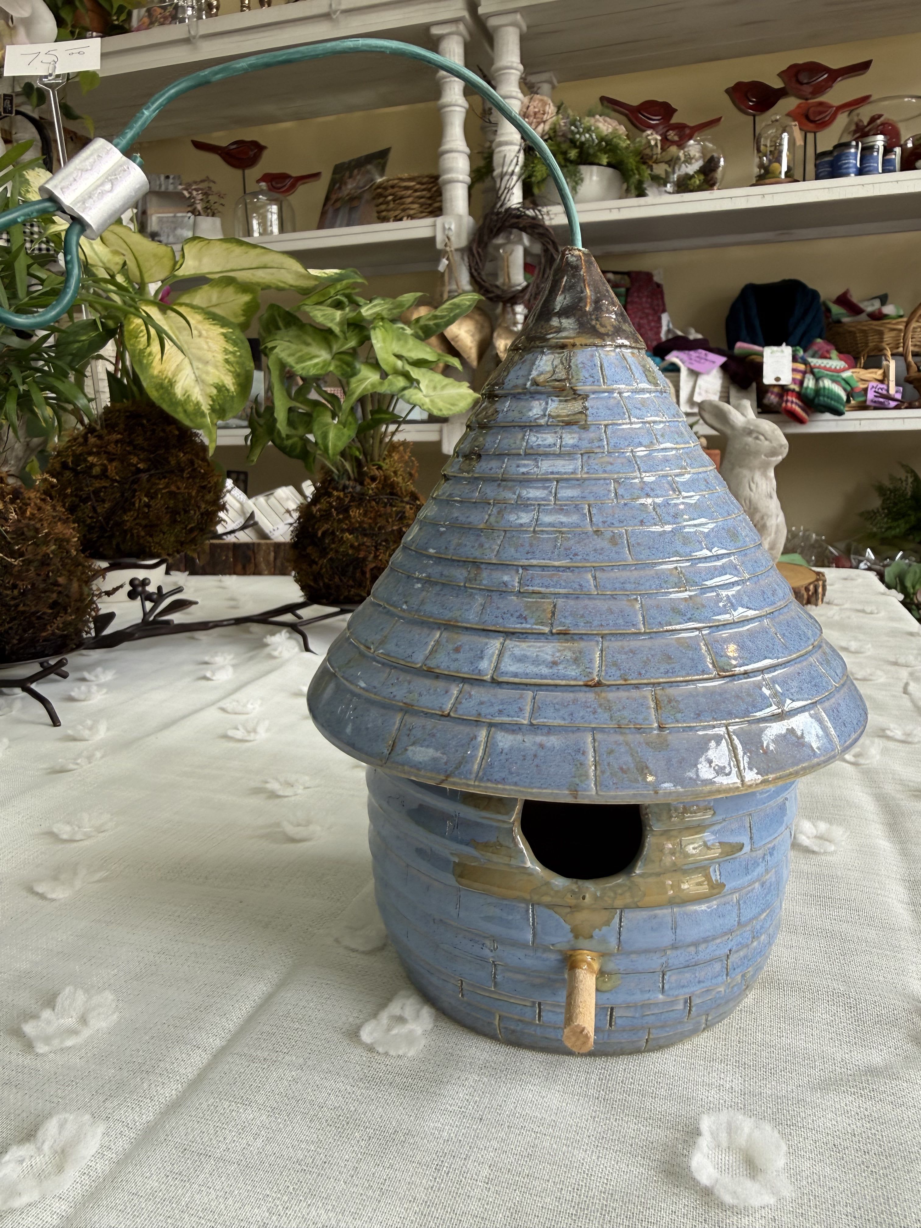 Bird feeder - A charming glazed ceramic birdhouse in mottled blue makes a playful and thoughtful gift for Mother's Day, a housewarming, or "just because" moments when you want to delight someone who loves garden whimsy. This rustic, rounded-base bird feeder reads handmade and inviting-its tall conical roof with brick-like texture, circular entry hole, and tiny perch give it a cheerful, cottagey presence that will make the recipient smile.  Finished in cool blue with touches of white and a subtly weathered glaze, the piece works equally well indoors on a sunny windowsill or outside on a sheltered porch or patio as a decorative accent. Sized to tuck easily into existing décor, it complements seasonal displays from spring and summer to autumn and winter and pairs nicely with potted herbs, small florals, or a simple ribbon for a birthday, anniversary, or retirement gift.  Whether you're marking a graduation, saying "thank you," sending get-well wishes, or adding a special touch to wedding or holiday décor, this ceramic birdhouse sends a message of care and thoughtfulness. Lightweight and ready to place, it requires only a protected spot outdoors if used as an actual bird feeder-otherwise it brings cheerful texture and color to interior spaces year-round.