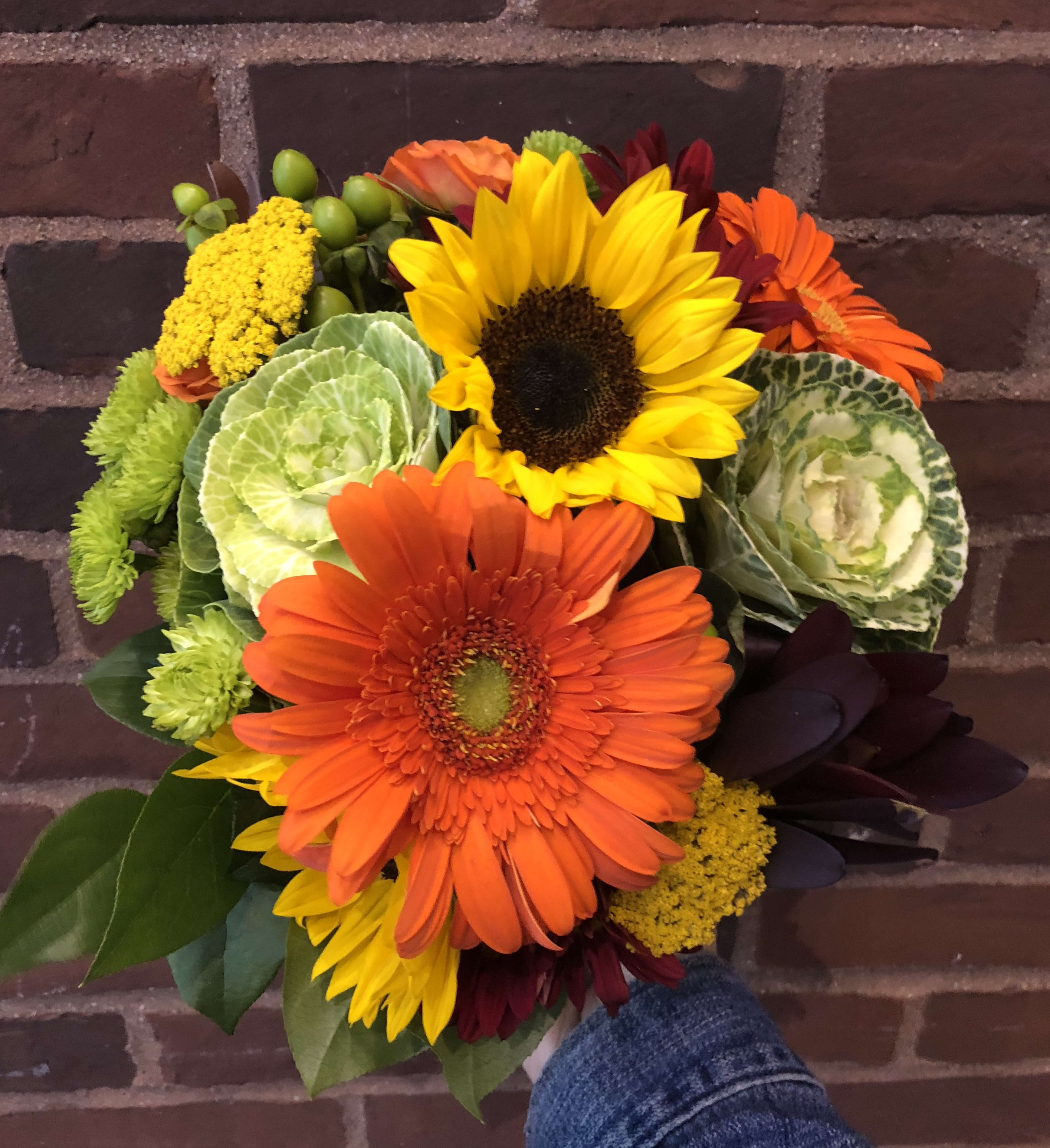 Bouquet of sunflowers, orange gerbera daisies, and green ornamental cabbage