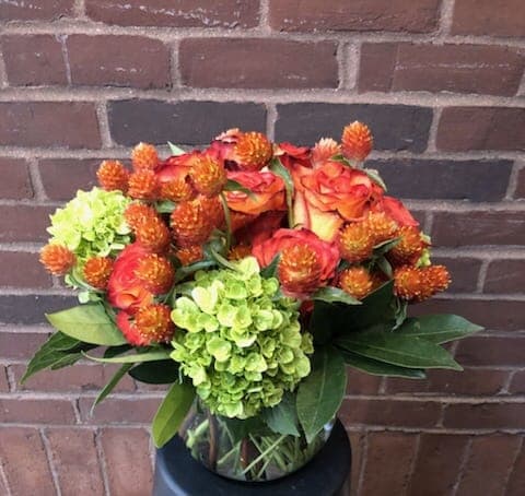 Bouquet of orange roses and green hydrangeas in a glass vase