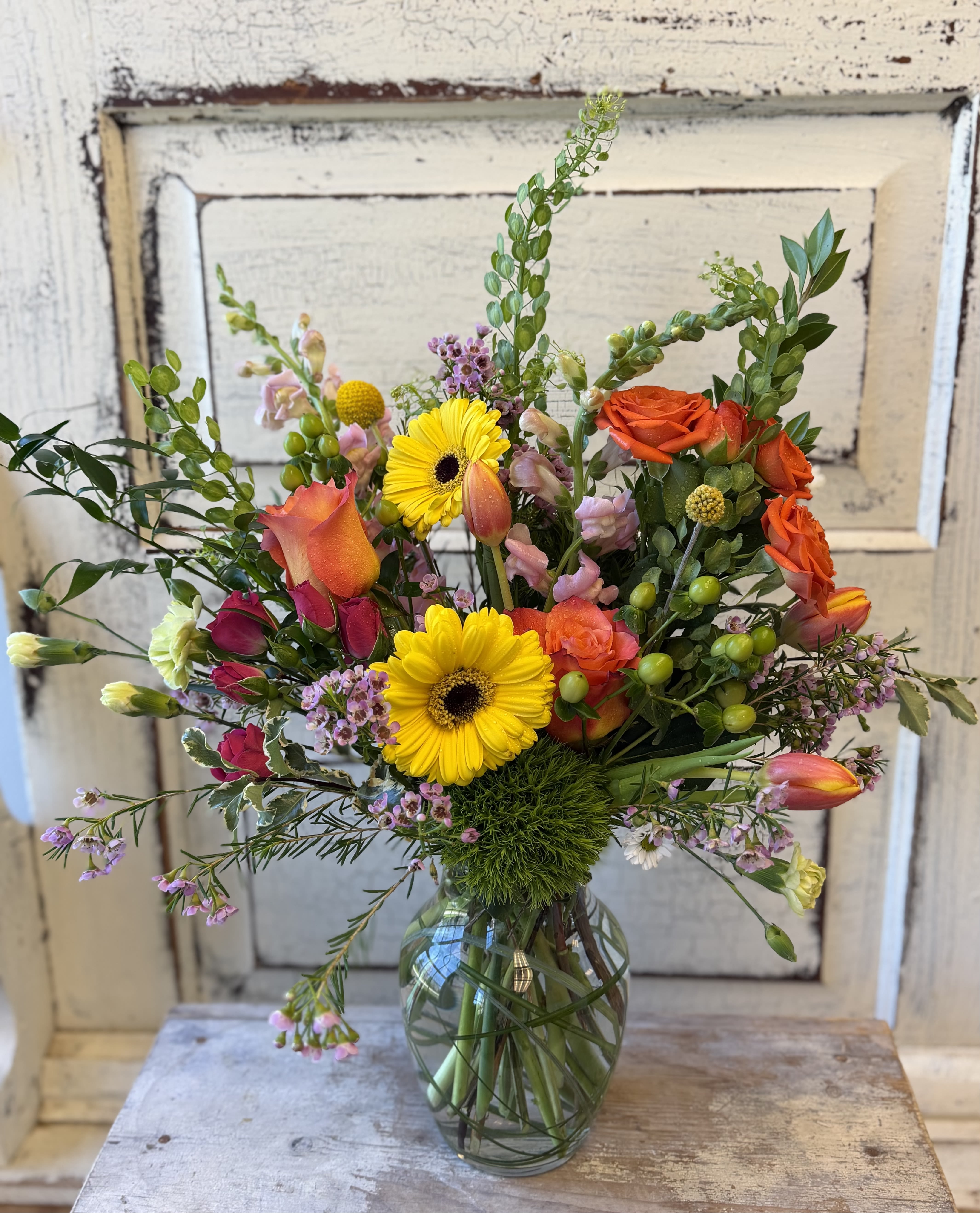 Citrus Splash - Unique blooms in a fun citrus color scheme are arranged in a small glass vase. Flower varieties may vary based on our weekly inventory but will reflect the theme.