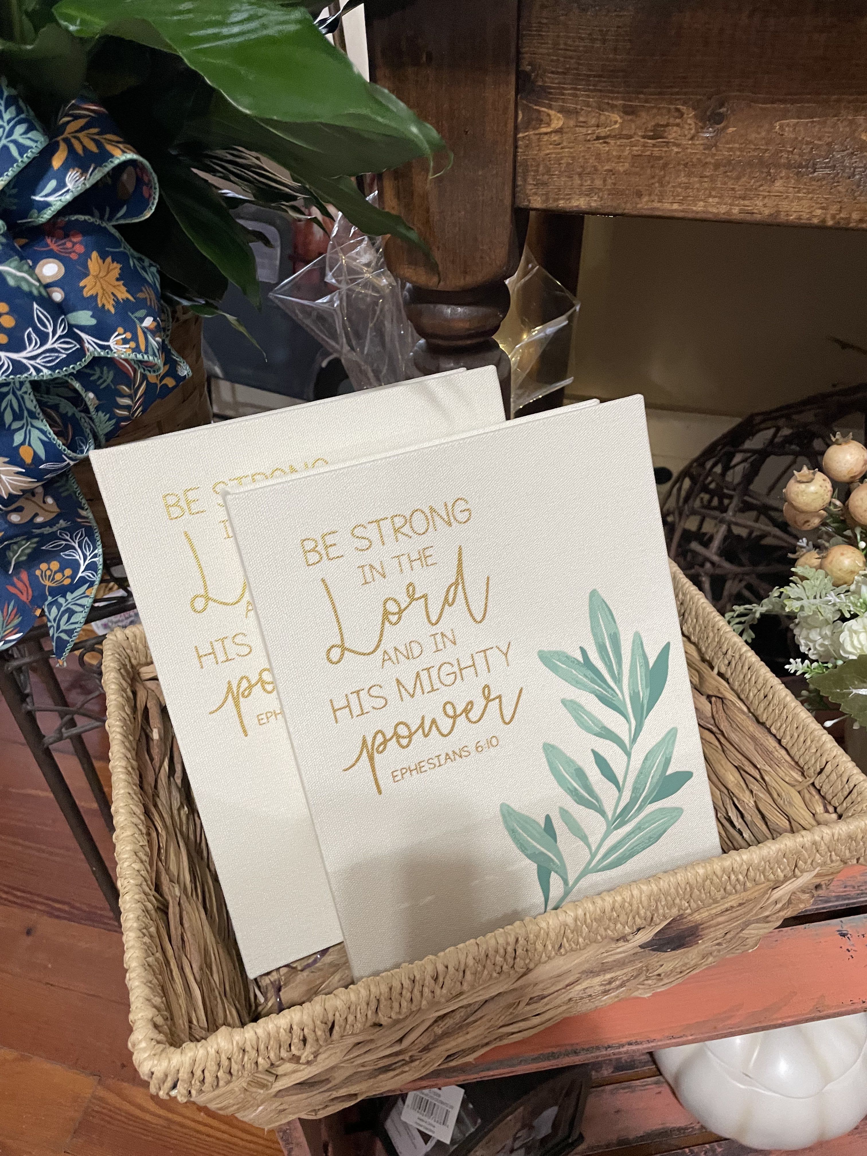Two decorative canvas signs in a woven basket with gold lettering