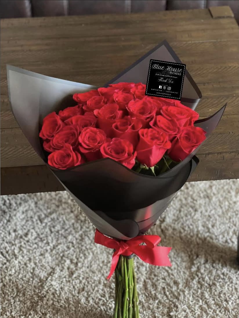 Bouquet of red roses wrapped in black paper with a red ribbon