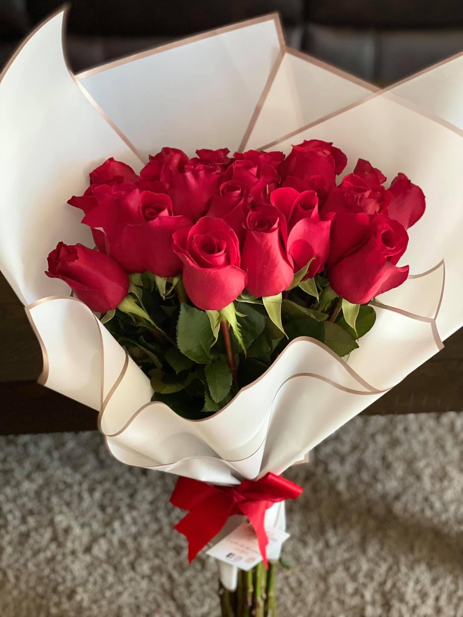 Bouquet of red roses wrapped in white paper with a red ribbon