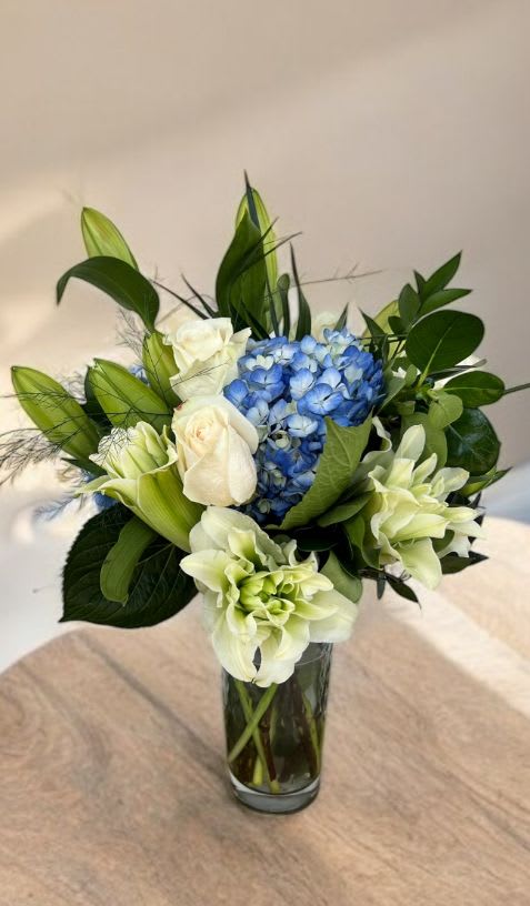Blue hydrangeas and white roses in a clear glass vase