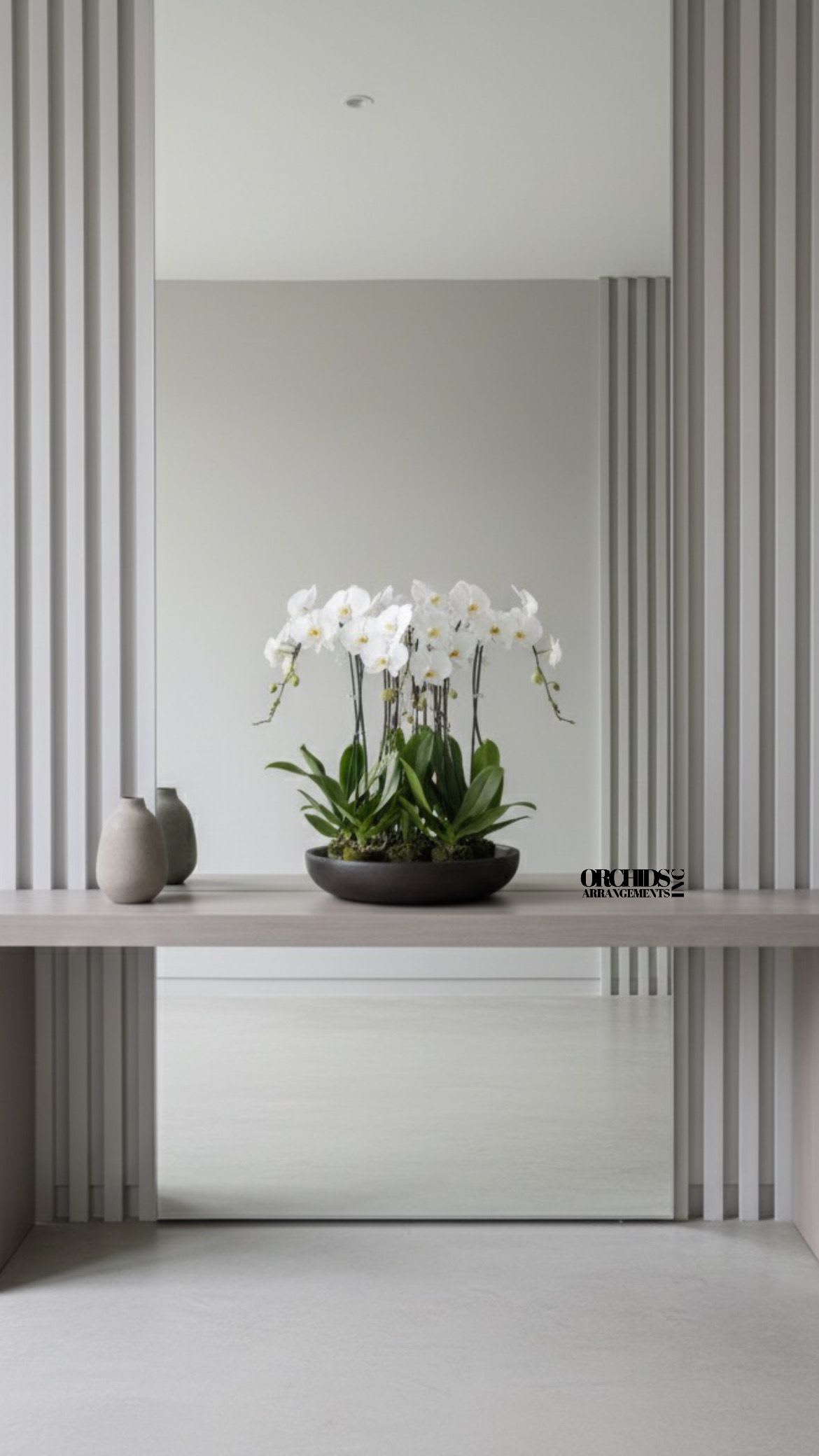 White orchid arrangement in a shallow dark bowl on a table