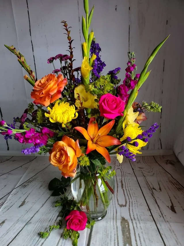 Colorful mixed bouquet in a clear glass vase with roses and lilies
