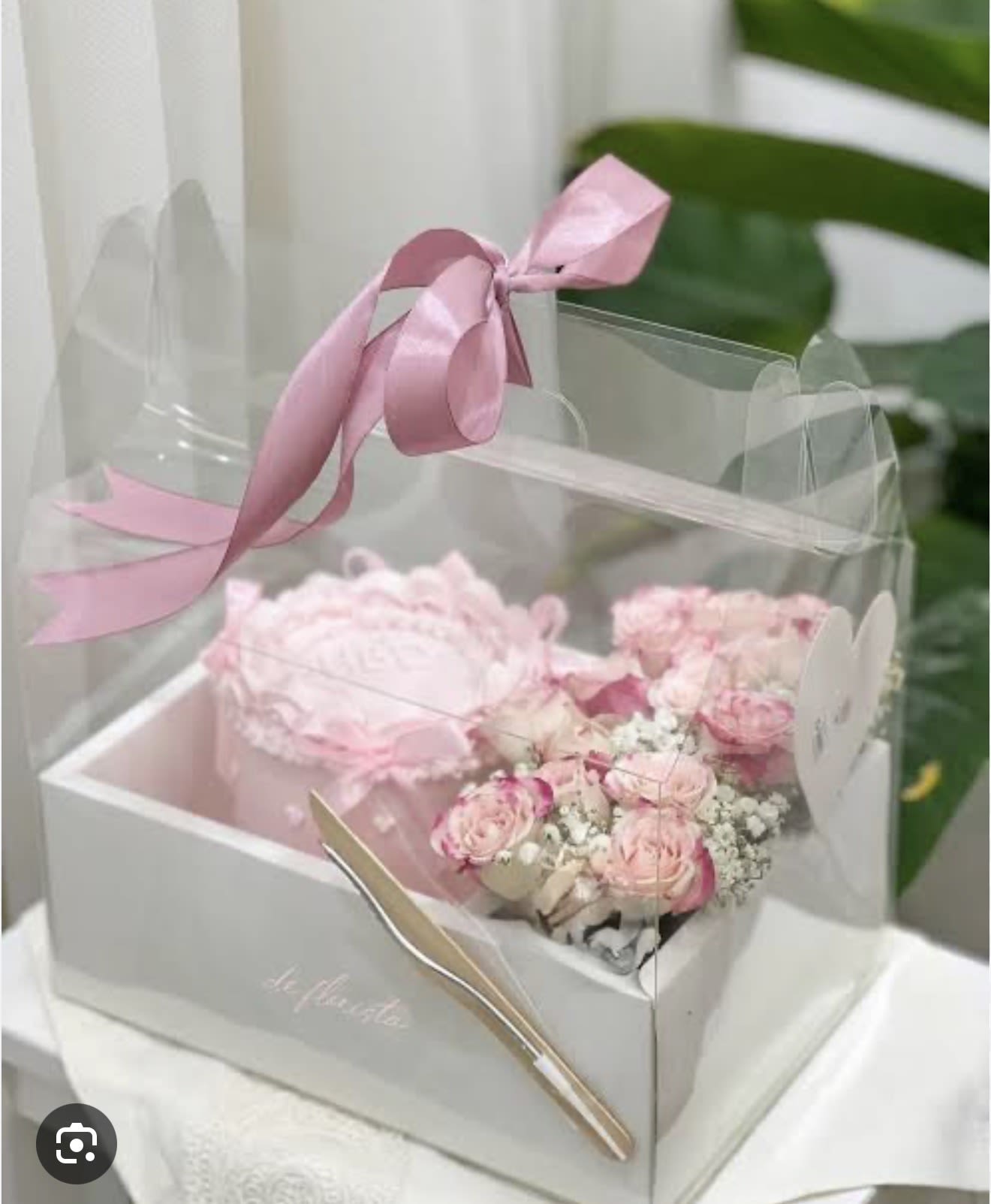 Cake and Flowers - A petite pink cake paired with a compact cluster of blush roses and tiny white fillers creates an instant "happy birthday" or romantic surprise-this flower arrangement and cake gift set is perfect as a birthday bouquet alternative or an anniversary treat. The presentation reads sweet and elegant: a clear gift box or pastel pink box framed with soft pink satin ribbon and a neat bow makes the moment feel polished and intentionally celebratory for the person you're honoring.  Inside you'll find a small decorated cake beside a tightly arranged cluster of roses in mauve, blush, lavender and white tones, accented by green foliage and delicate filler blooms; some versions use high-quality silk flowers for long-lasting keepsakes. The set comes wrapped in clear plastic within a white or pink gift box, finished with a pink ribbon bow and ribbon tie-ready to give without extra fuss.  This is the kind of gift that makes someone feel truly seen on birthdays, anniversaries, or any romantic celebration-thoughtful, feminine, and sweet. Because the flowers include silk options, the floral portion can be kept as a memento; the cake is intended to be enjoyed right away. Order with standard sizing and packaging as shown for a polished, gift-ready presentation.