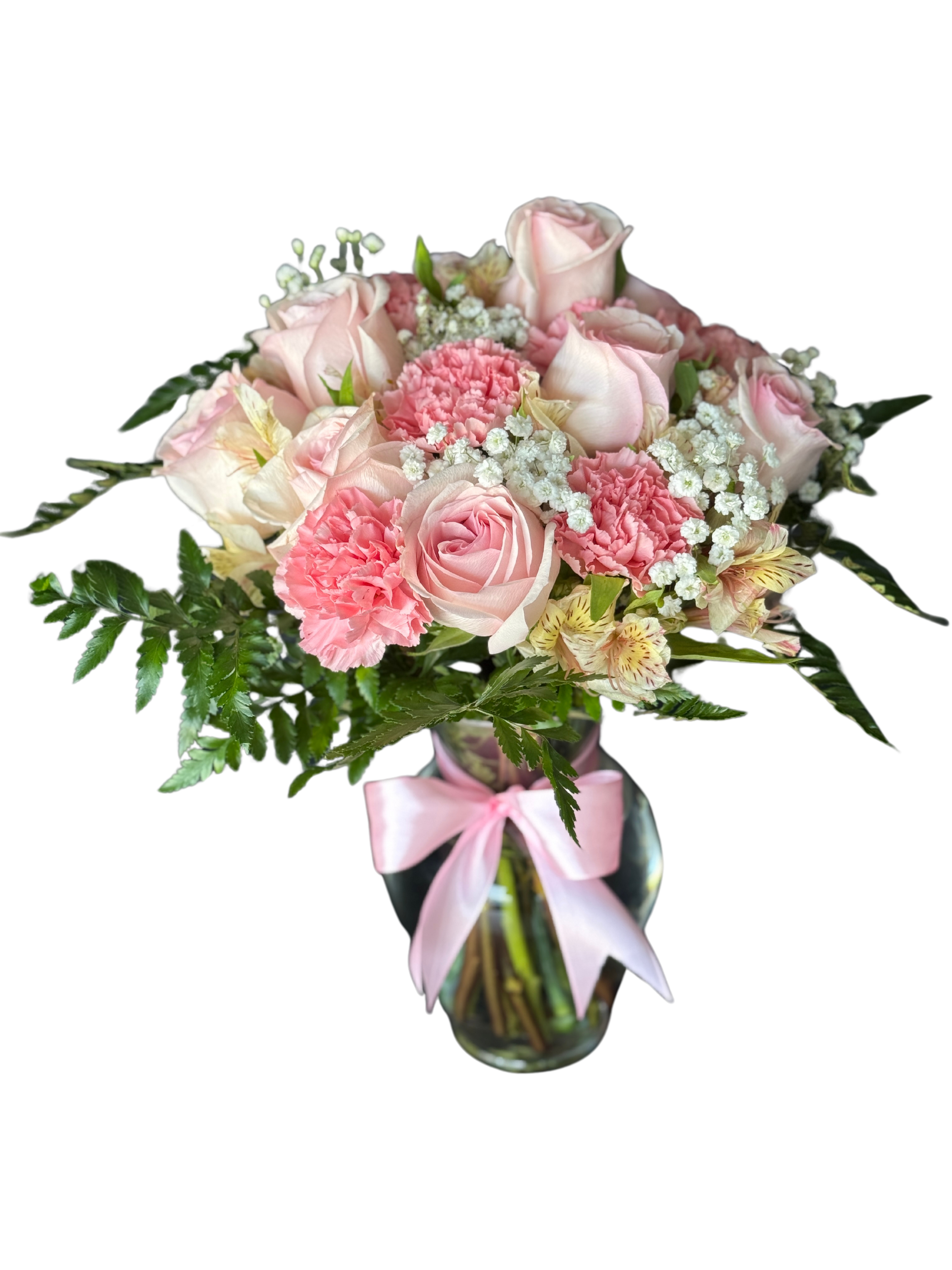 Bouquet pink in a vase - Soft pink roses and ruffled carnations form a rounded, romantic birthday bouquet arranged in a clear glass vase-perfect for anniversaries, Mother's Day, or a heartfelt "thinking of you." The pale pink ribbon tied around the vase adds a delicate finishing touch that makes the recipient feel cherished the moment they see it.  This pink and white arrangement pairs blush roses with soft carnations and tiny white filler blooms, punctuated by fresh green foliage for light contrast and texture. The flowers are neatly clustered for a full, domed silhouette and come ready in a clear glass vase-no extra assembly required.  Ideal for the person you want to make feel truly seen, this bouquet sends a gentle, classic message of affection and appreciation. Vase care is simple: change the water every 2-3 days and trim stems slightly to prolong freshness; sizing fits standard tabletop displays for home or office.