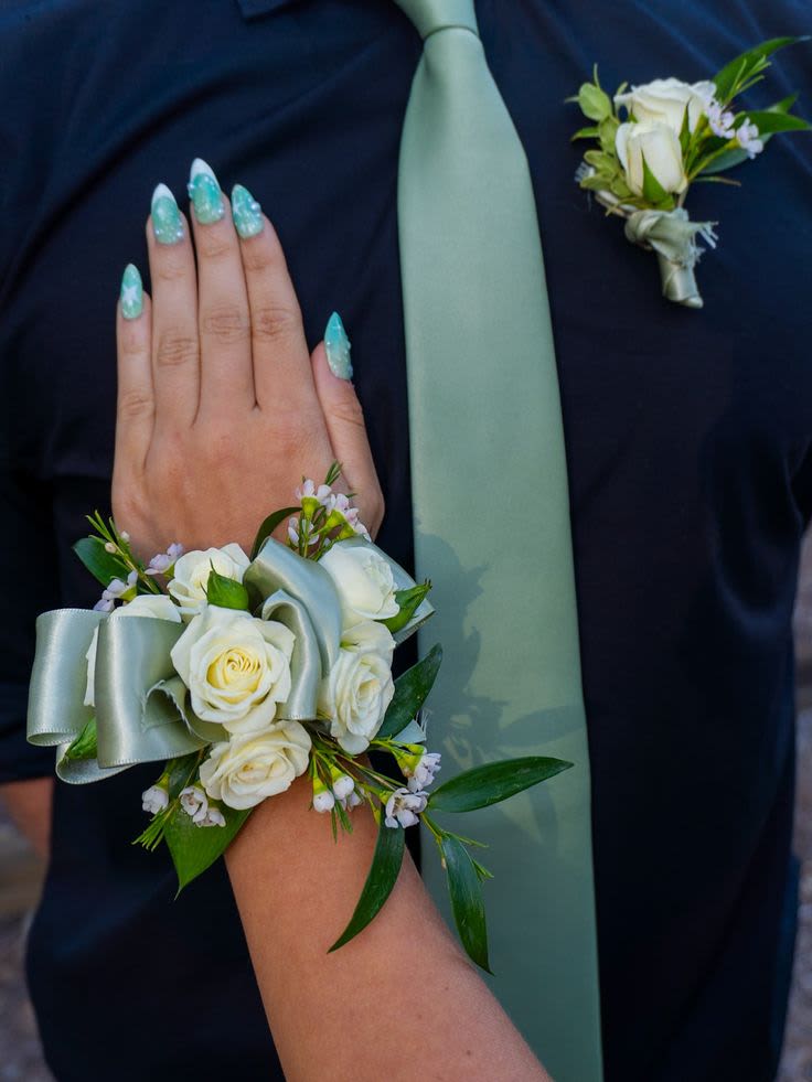 Sage Garden Corsage &amp; Boutonniere Set - This matching corsage and boutonniere set features fresh ivory spray roses, delicate wax flowers, soft greenery, and sage satin ribbon accents for a romantic and elegant prom look.  Designed with fresh flowers and carefully coordinated details, this set brings a soft garden-inspired touch to your special night.  Includes: • Wrist corsage • Matching boutonniere • Fresh flowers • Satin ribbon detailing  If you would like a different ribbon color to match your outfit or prom theme, please leave your preferred color in the notes section at checkout.   This design can be customized to match your dress or prom colors. Please leave your dress color or inspiration details in the notes section at checkout, and we will create a beautifully coordinated set just for you.  