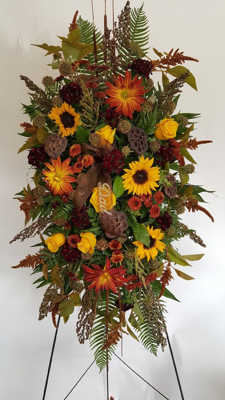 Tall standing floral spray with sunflowers, roses, and autumn foliage