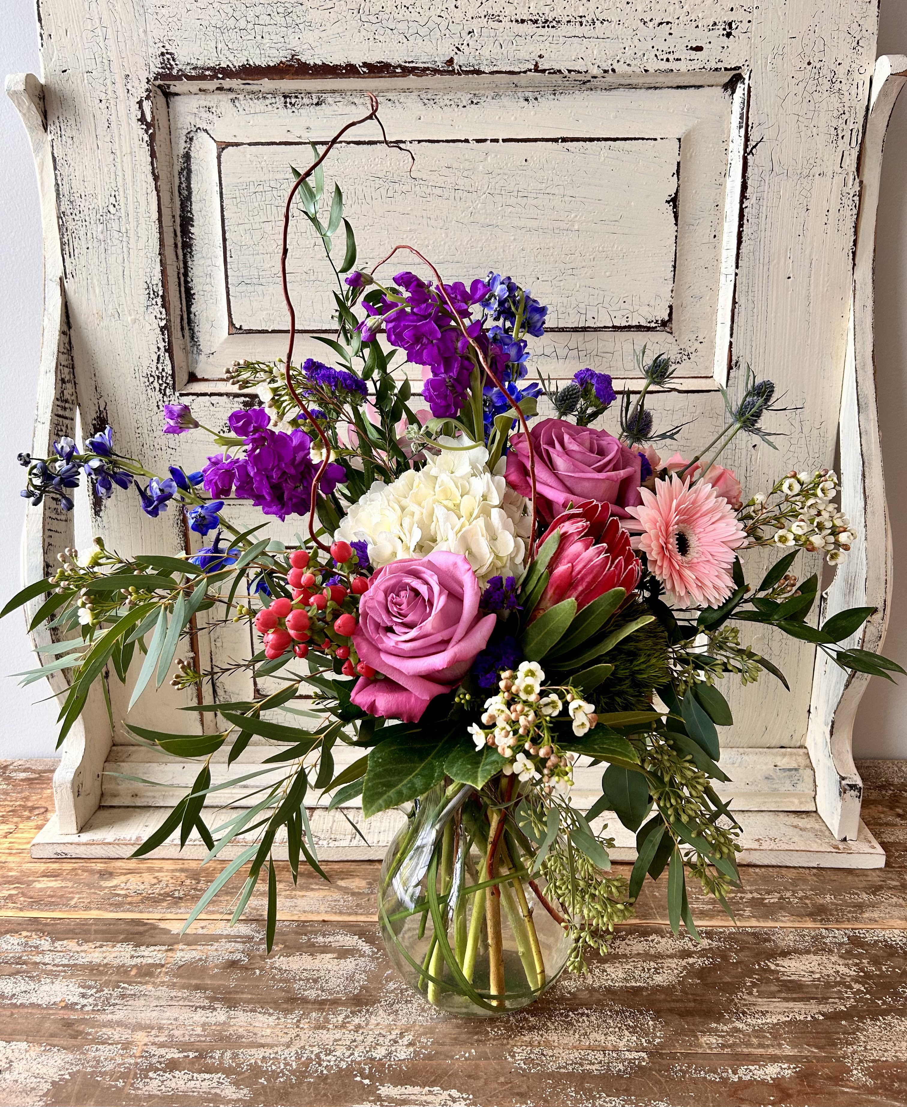 Mixed bouquet in a clear glass vase with pink, purple, white, and blue flowers