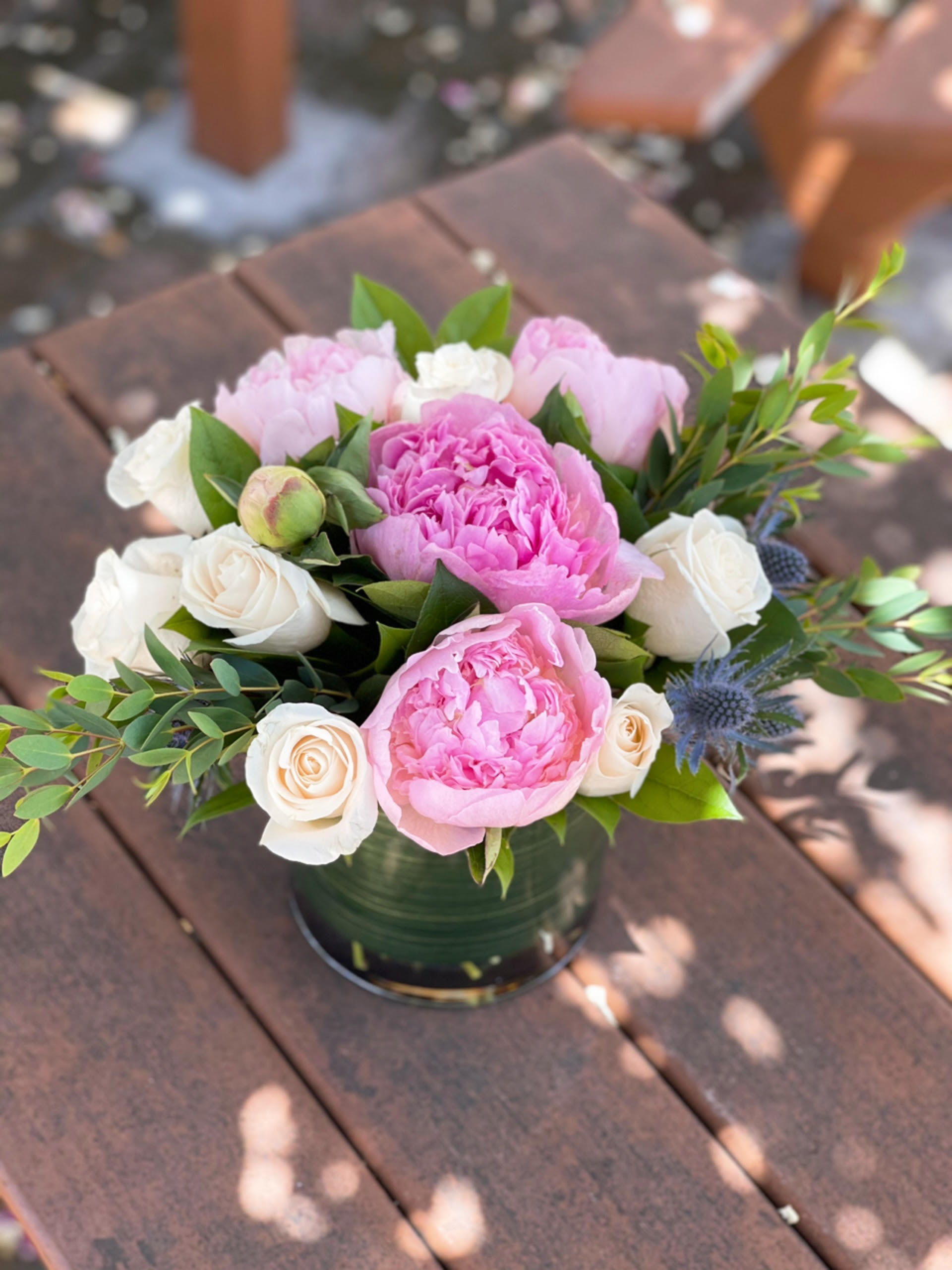 Pink peonies and white roses arranged in a low vase