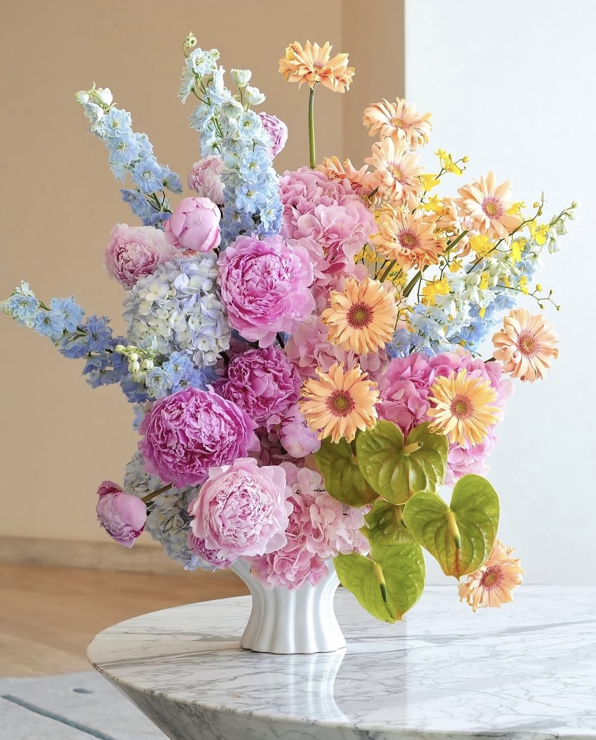 Colorful bouquet of pink, blue, and peach flowers in a white vase