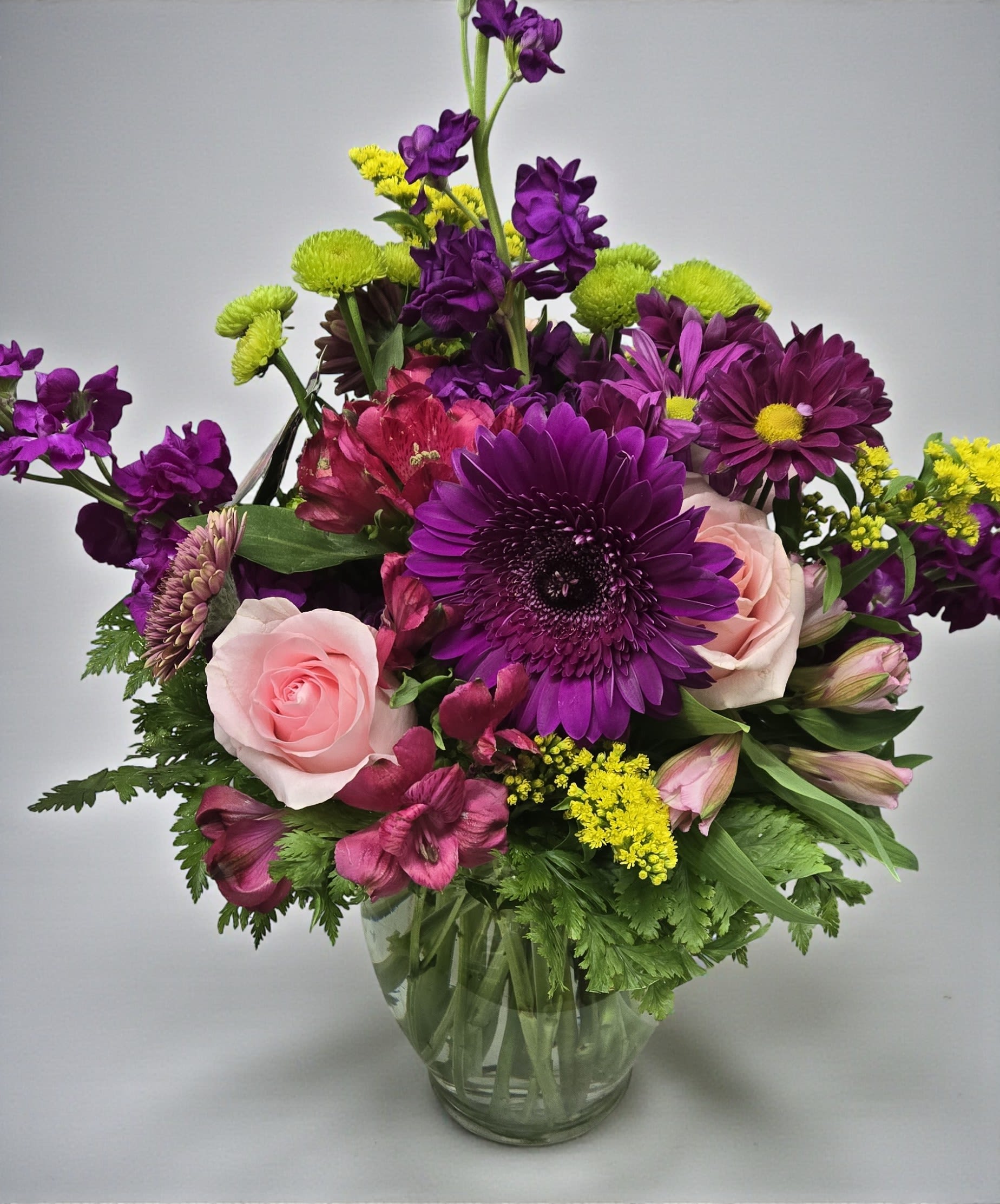 Purple and pink mixed bouquet in a clear glass vase