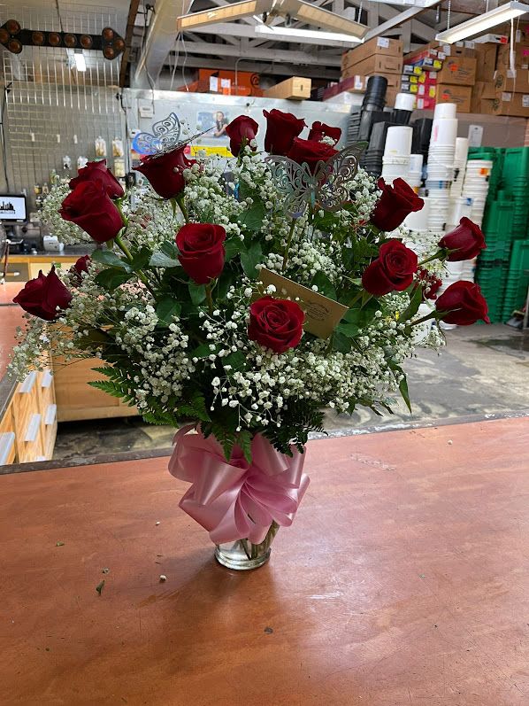 Bouquet of red roses and baby's breath in a glass vase with a pink ribbon