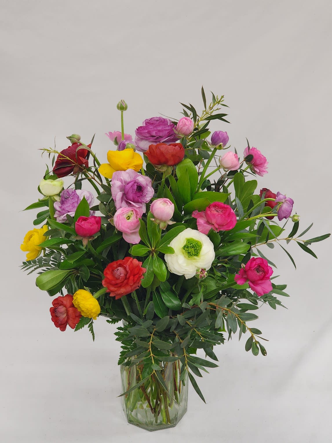 Mixed bouquet of colorful ranunculus in a clear glass vase