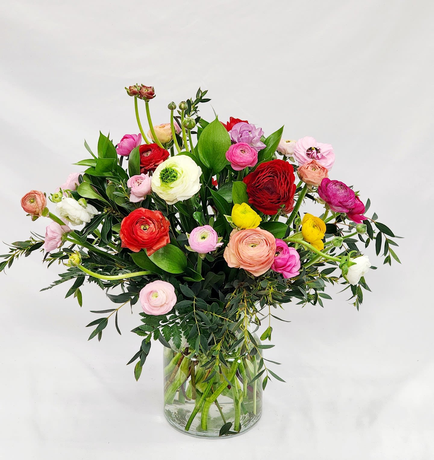 Mixed bouquet of colorful ranunculus in a clear glass vase