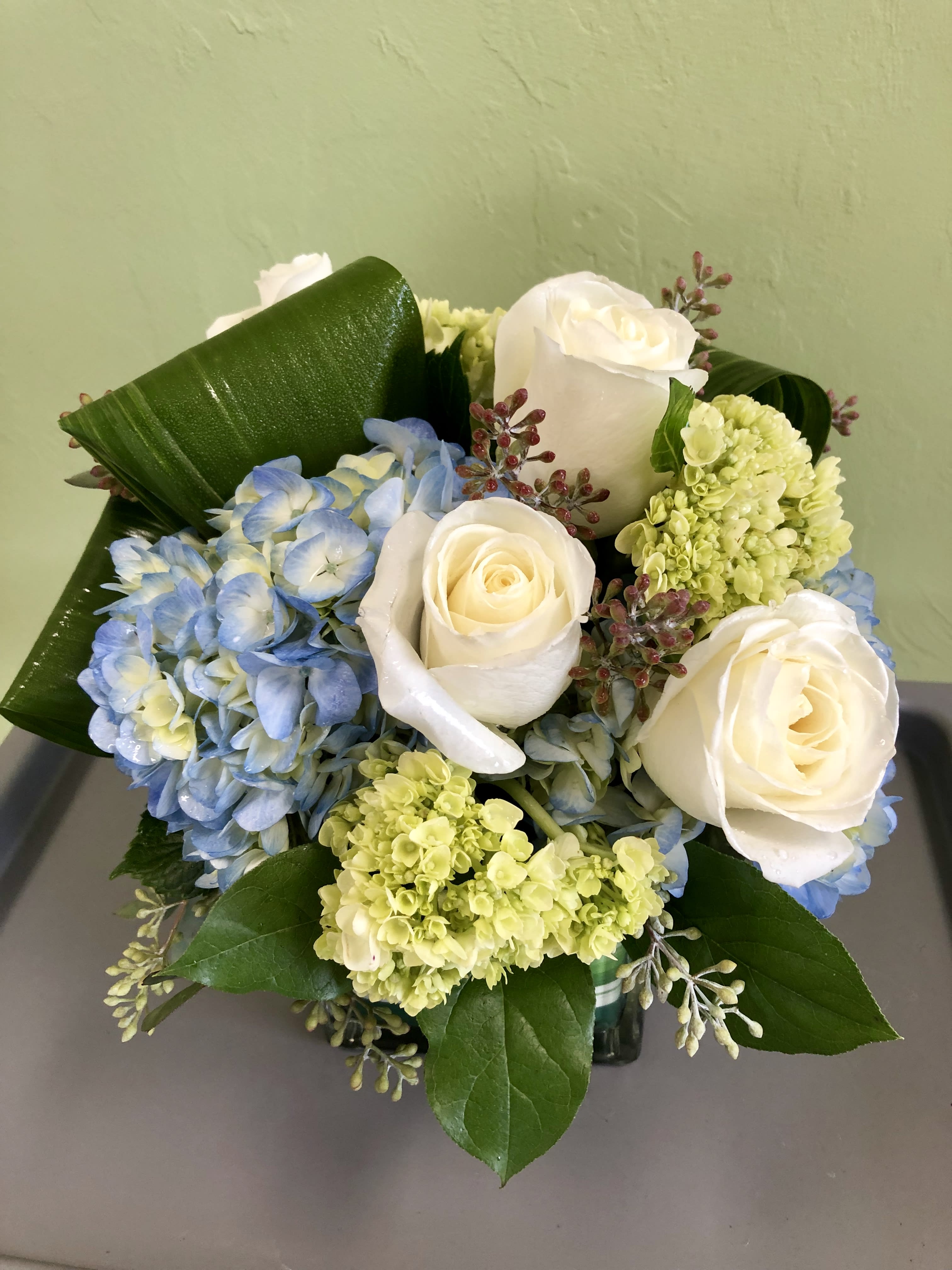 Bouquet of white roses and blue hydrangeas with green accents