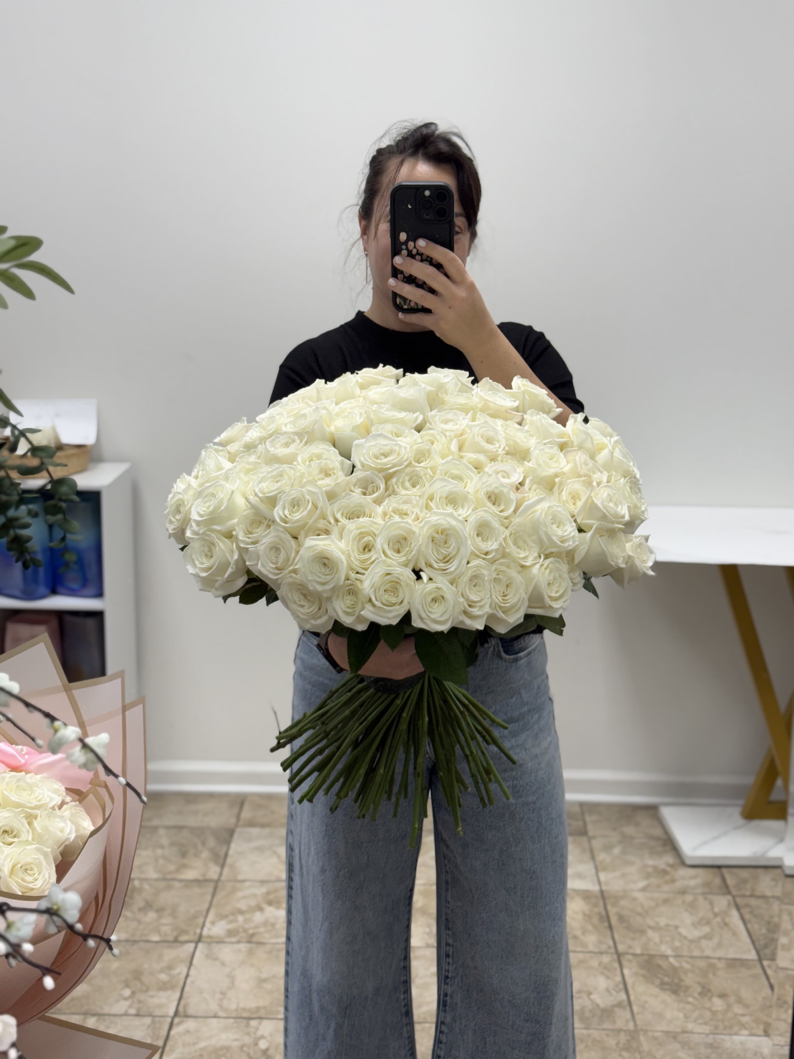 Large bouquet of white roses held by a person taking a mirror selfie