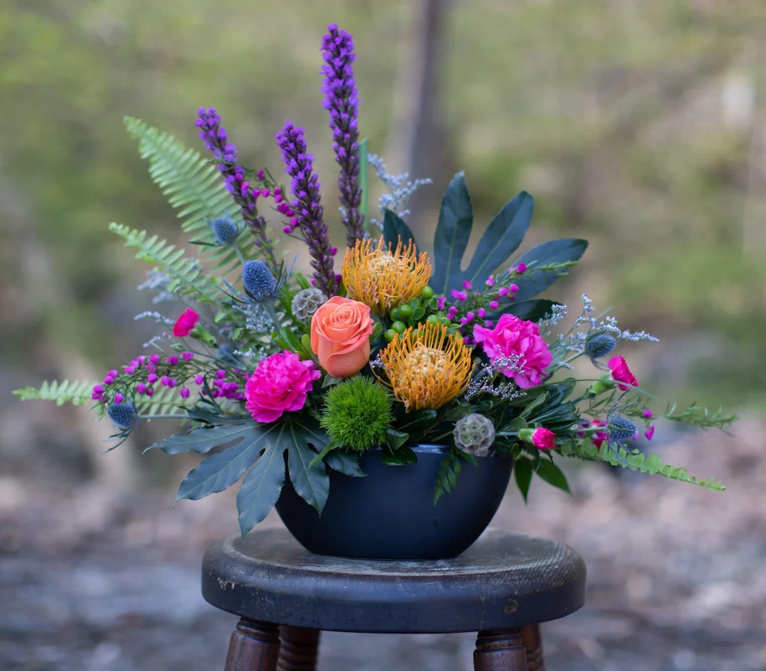 Colorful mixed flower arrangement in a dark bowl vase