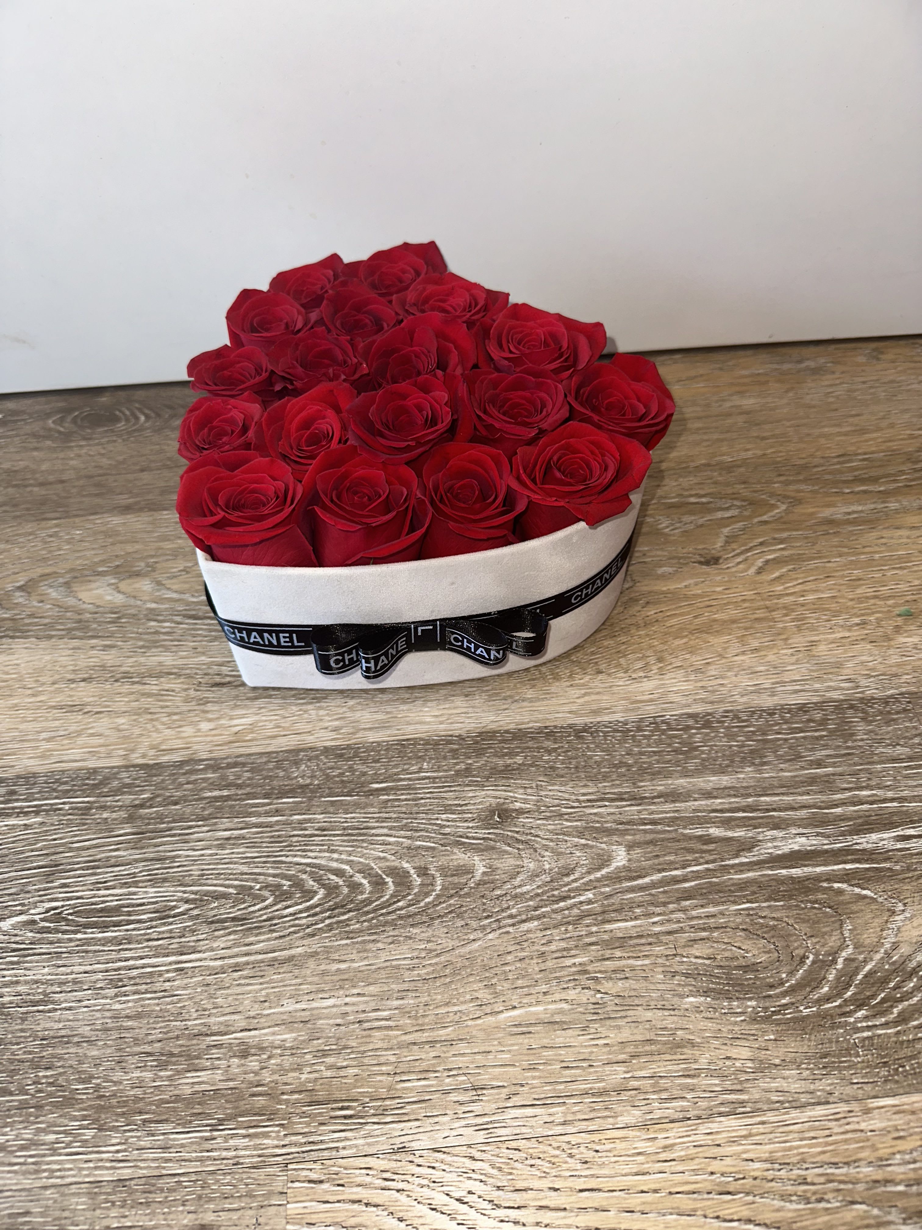 Heart-shaped box filled with red roses and a black ribbon