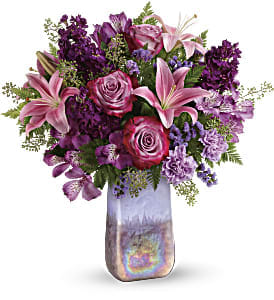 Teleflora's Amethyst Jewel Bouquet  - This bouquet features lavender roses, pink asiatic lilies, purple alstroemeria, lavender carnations, lavender sinuata statice, seeded eucalyptus, and leatherleaf fern. Delivered in an Amethyst Gemstone Art Glass vase. Approximately 18 1/2" W x 20 1/2" H