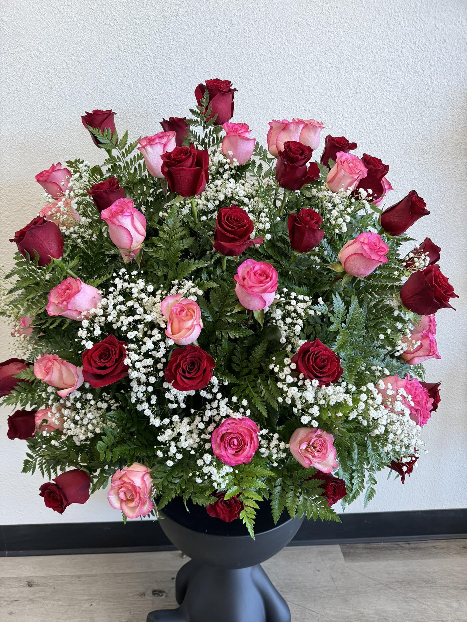 Large arrangement of red and pink roses in a black vase