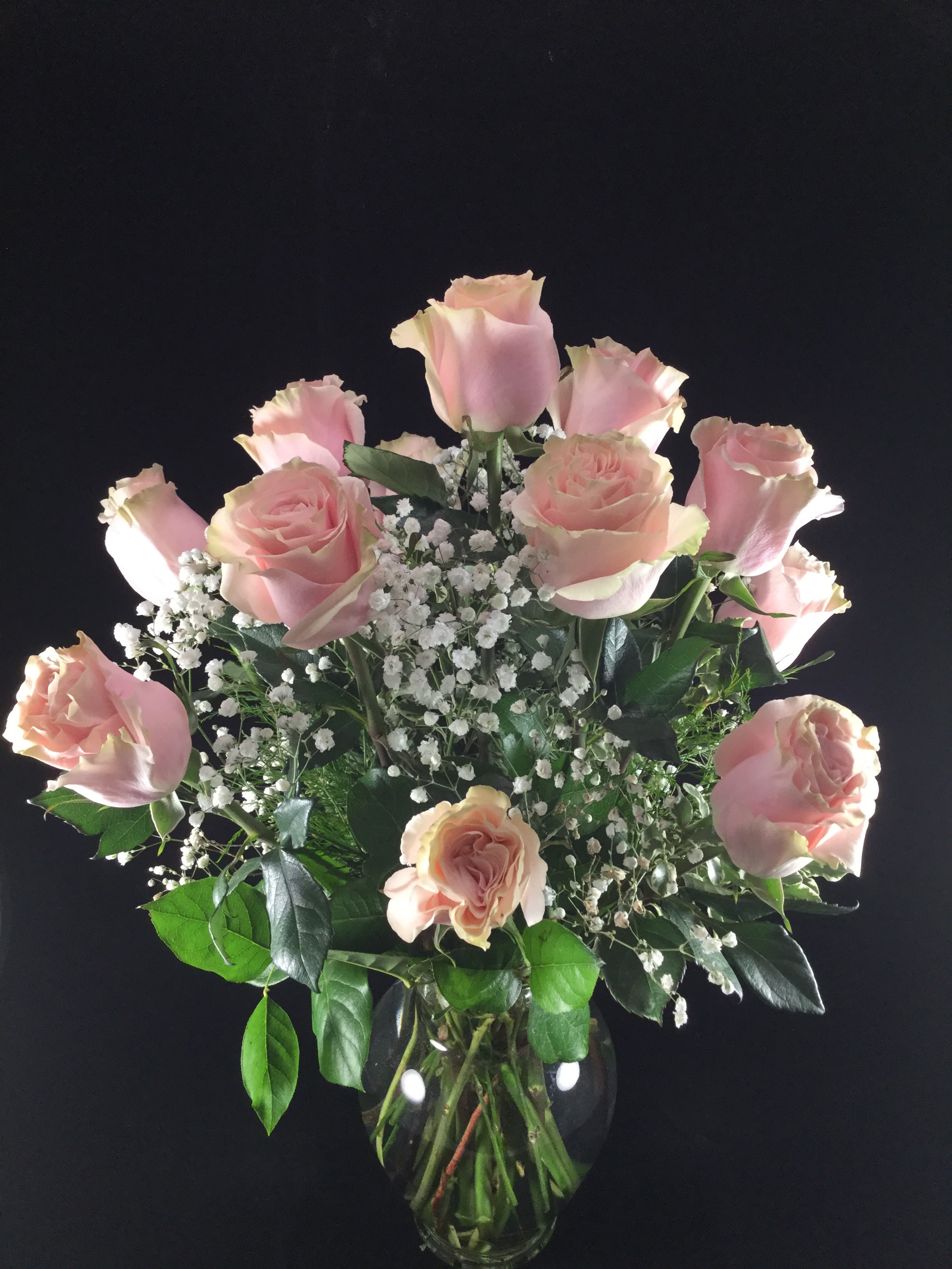 Pink roses arranged in a clear glass vase with white baby's breath