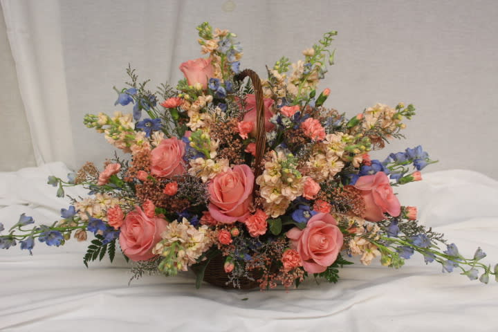 Basket arrangement of pink roses and blue flowers