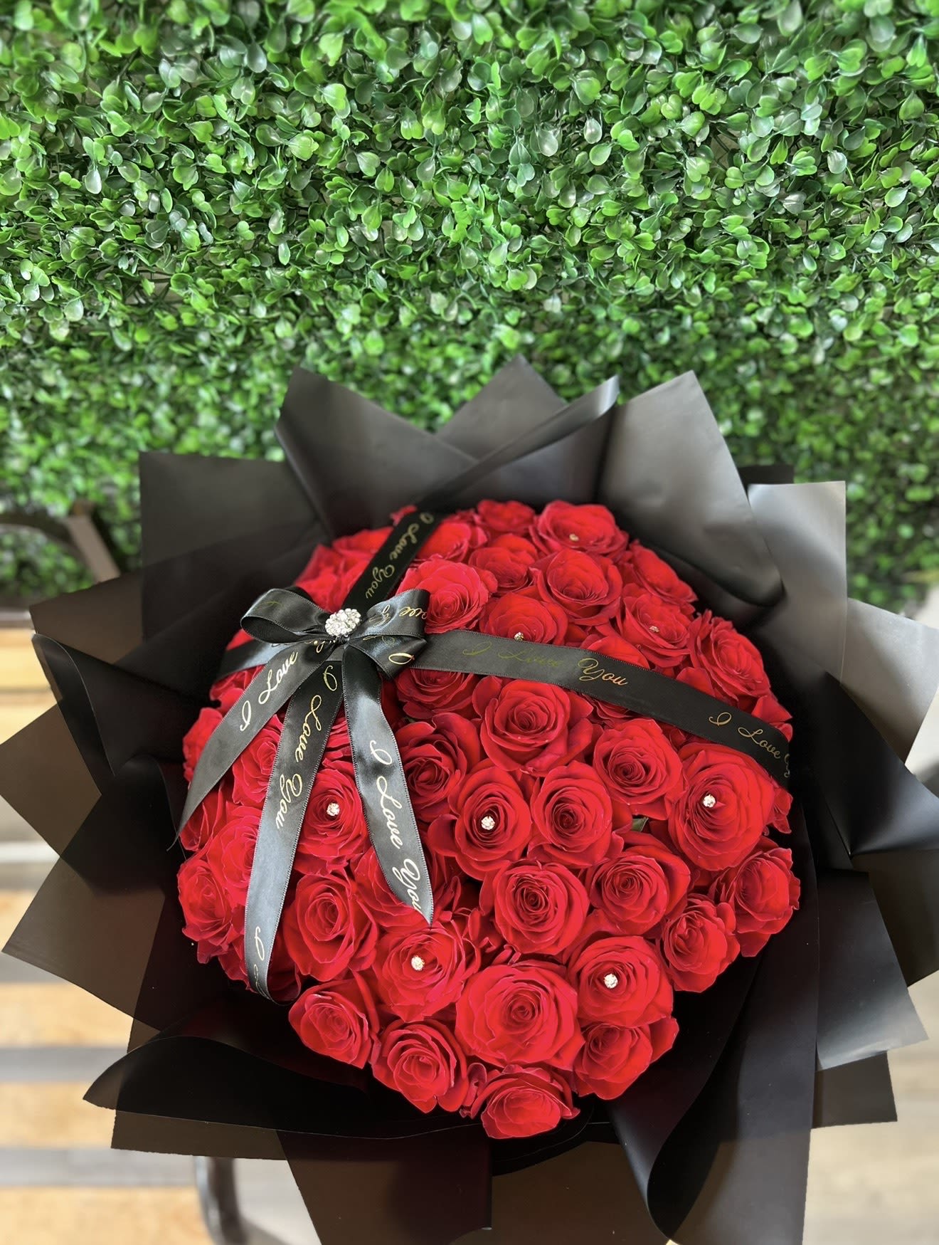 Large bouquet of red roses wrapped in black paper with a black ribbon