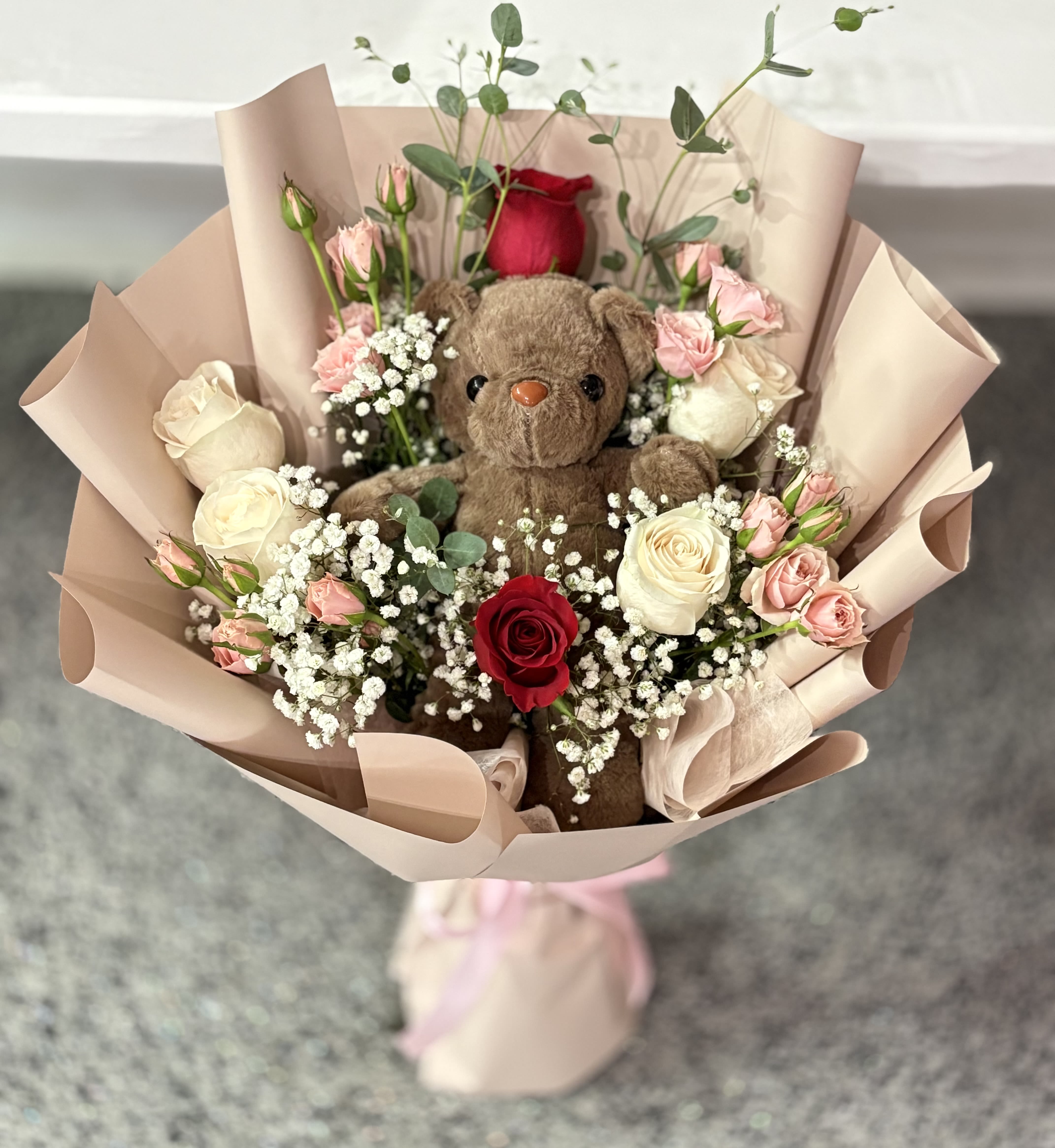 Bouquet with a teddy bear surrounded by roses and baby’s breath