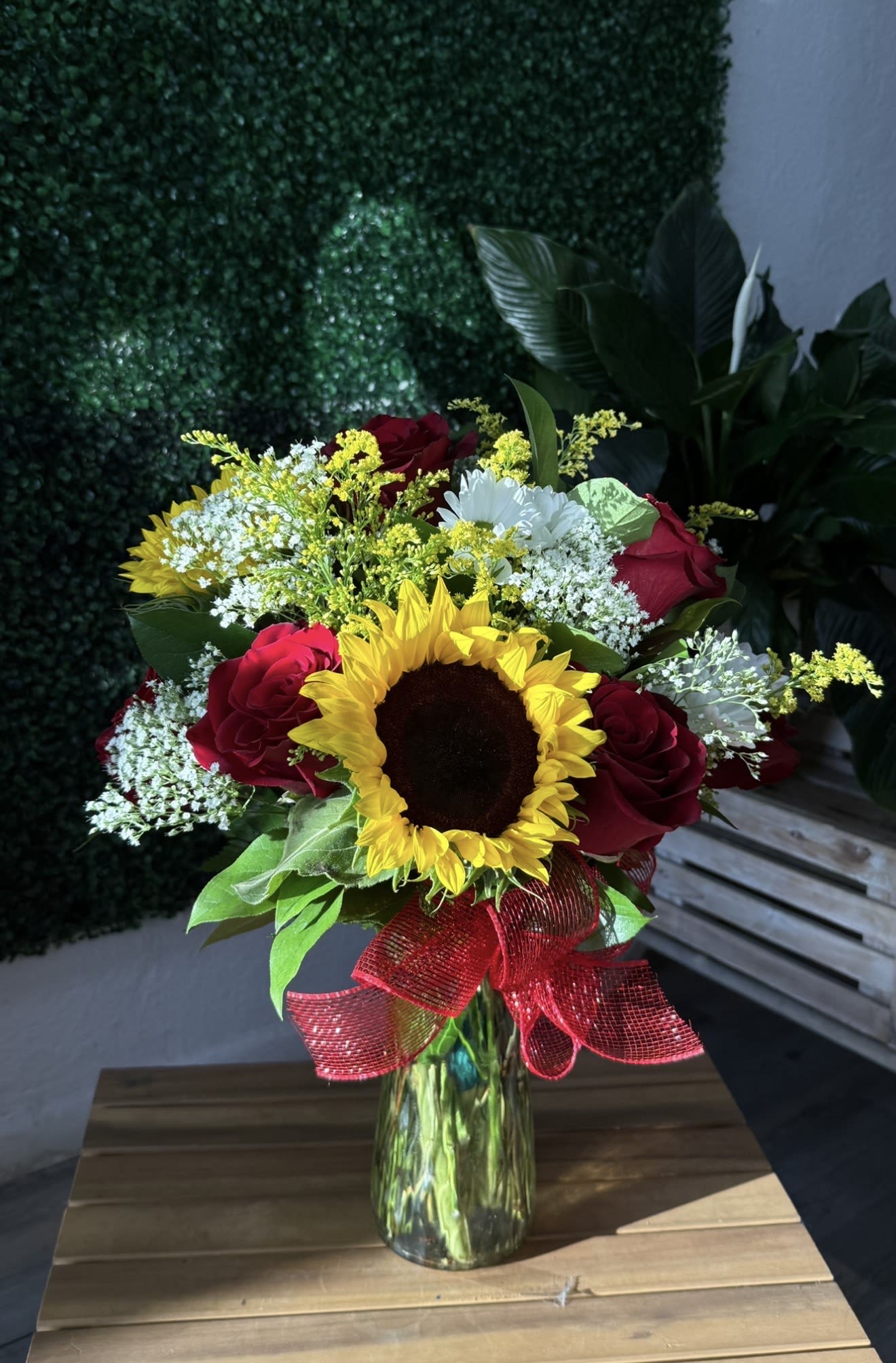 Sunflower and red rose bouquet in a glass vase with a red ribbon